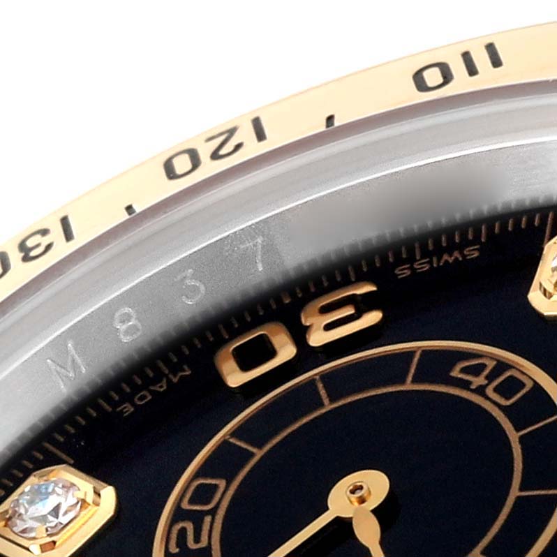 The image shows a close-up angle of the Rolex Daytona 116523 Men
s Steel and Gold (two tone) Black Dial 116523 Men
s Steel and Gold (two tone) Black Dial watch
s face, showcasing parts of the bezel, dial, and diamond marker.