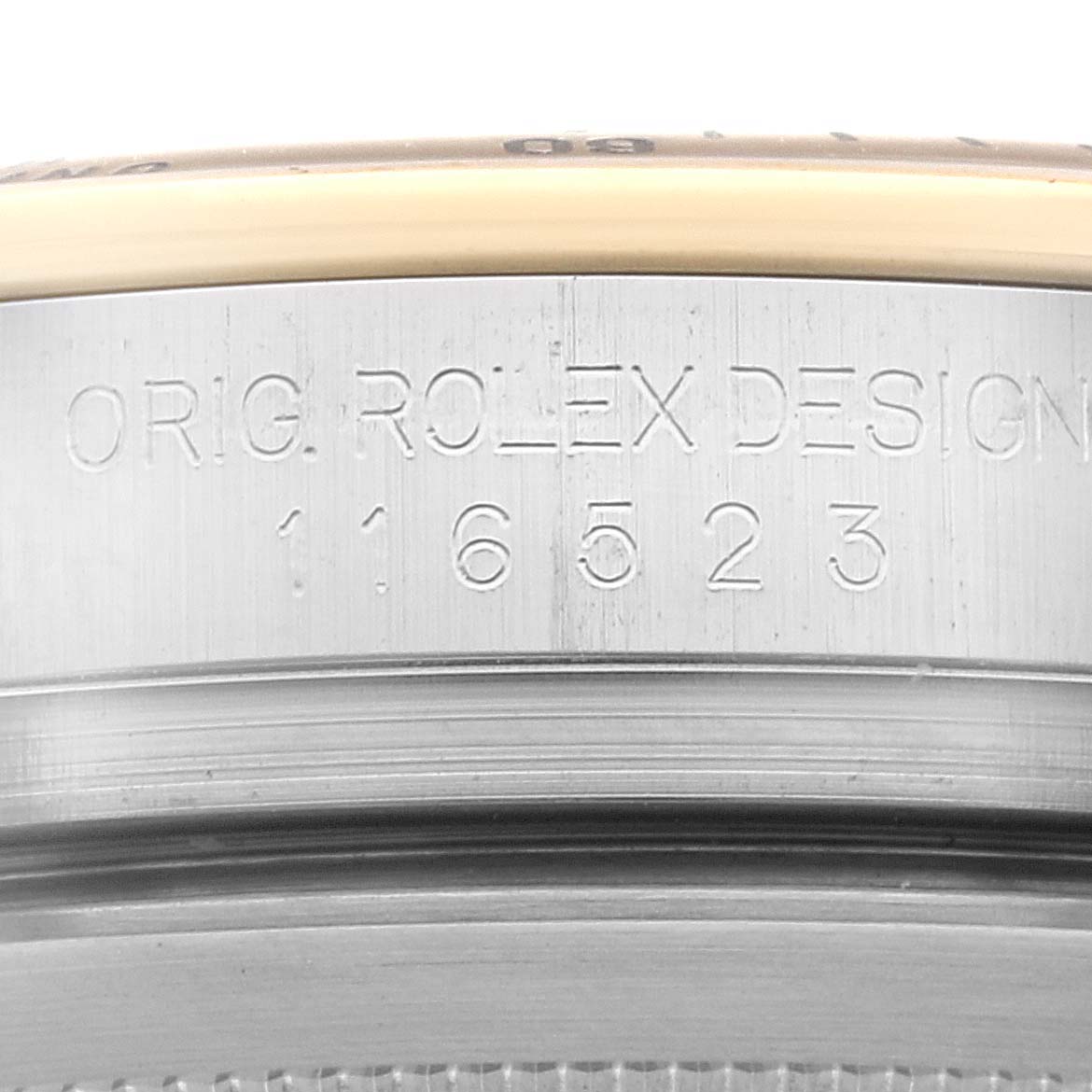 The image shows a close-up of the casing and bezel edges of a Rolex Daytona 116523 Men
s Steel and Gold (two tone) Black Dial 116523 Men
s Steel and Gold (two tone) Black Dial watch with its model number engraved.