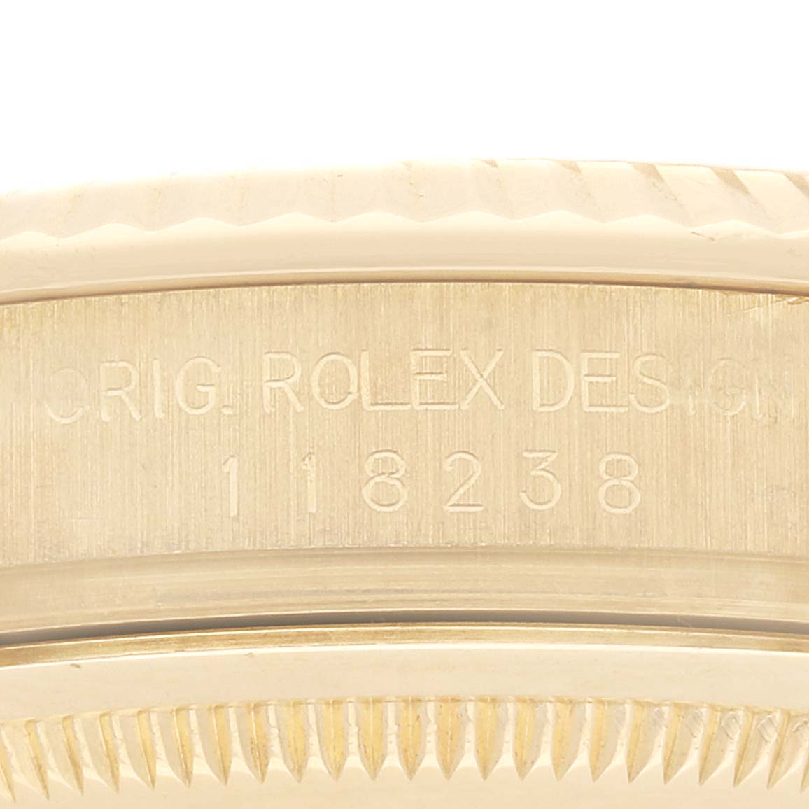 A close-up view of the side of the Rolex President 118238 Men's Yellow Gold Black Dial 118238 Men's Yellow Gold Black Dial model showing the engraved serial number and part of the fluted bezel.