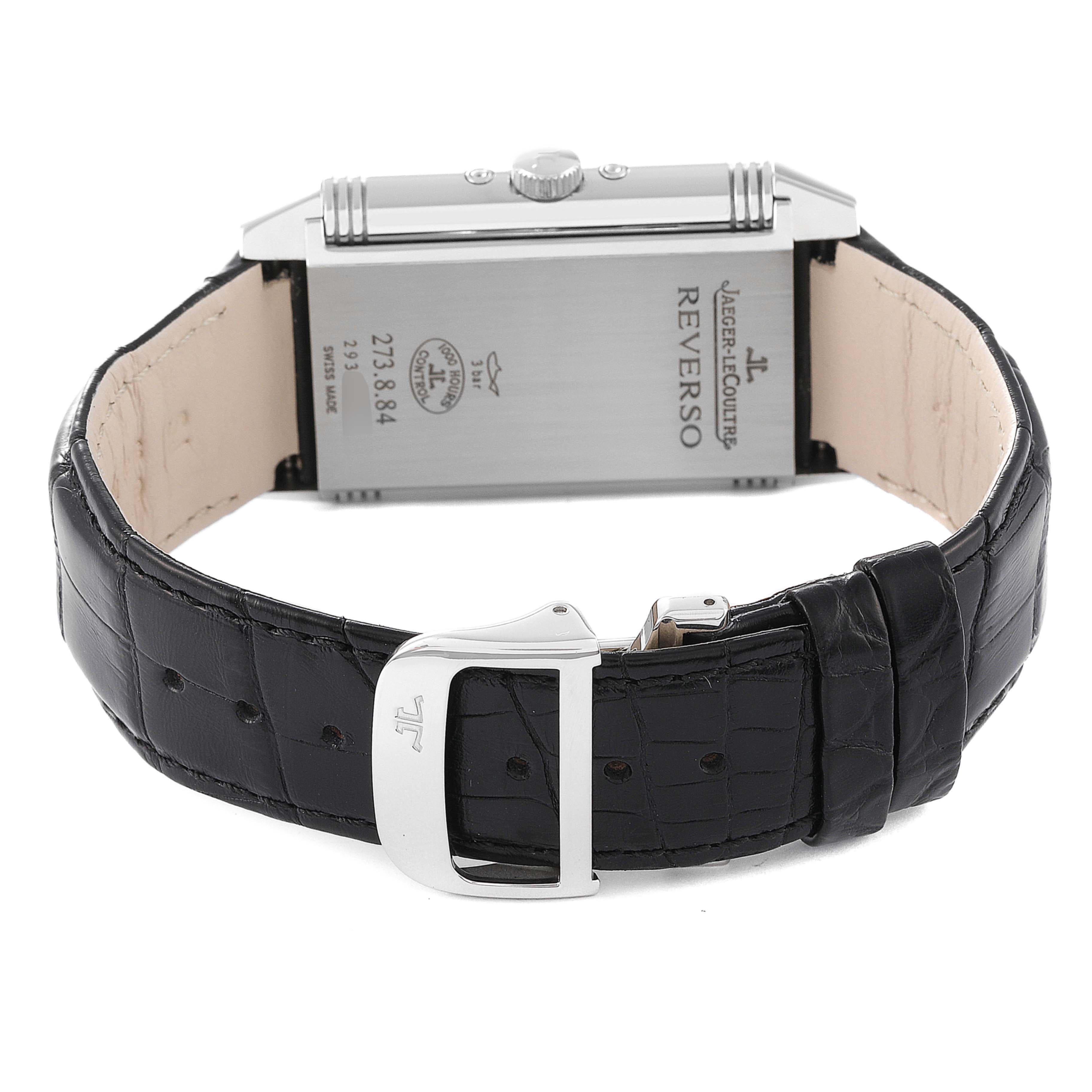 The image shows the back side of a Jaeger-LeCoultre Reverso watch, highlighting the engravings and black leather strap with a buckle.