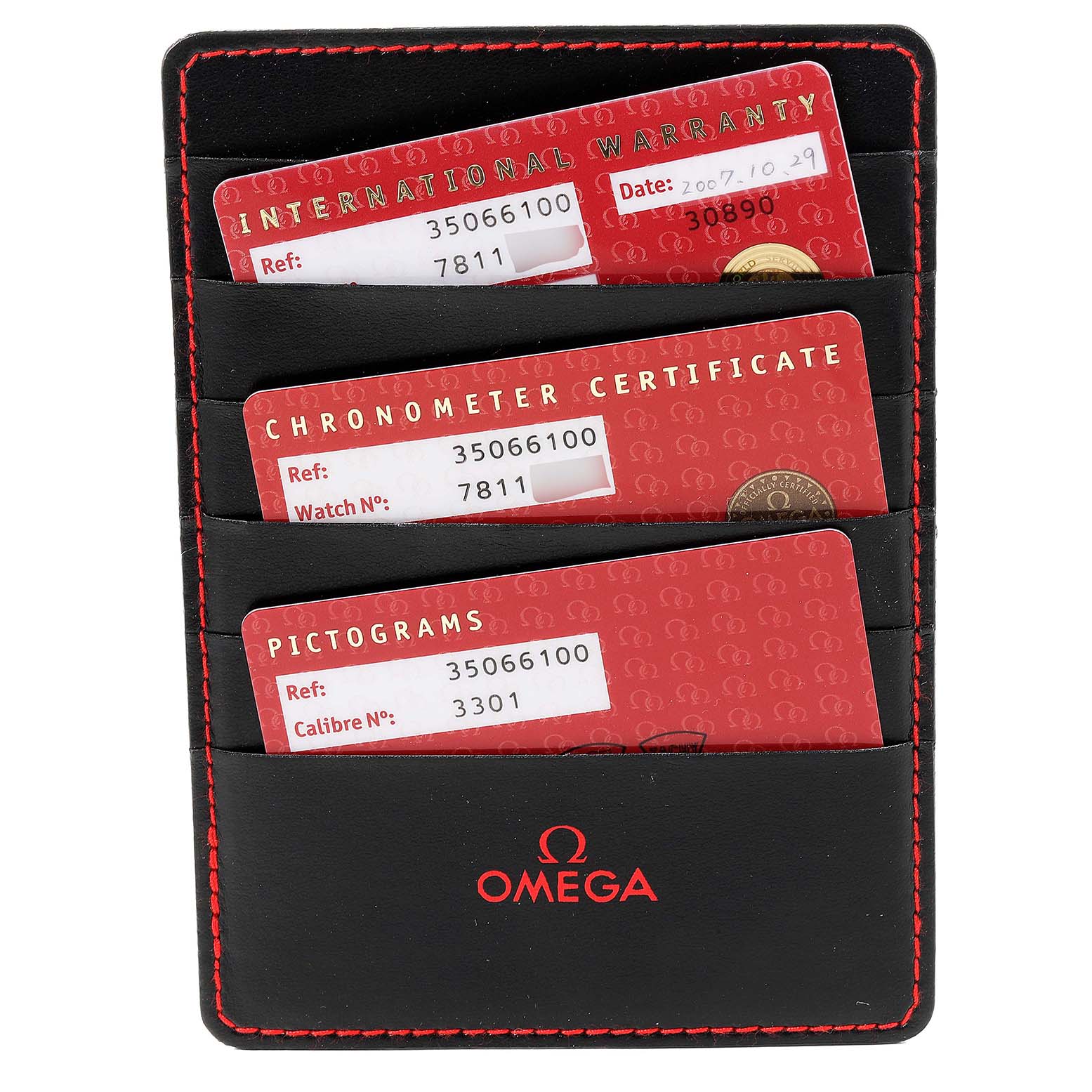 This is a top-down view of Omega Speedmaster 3506.61.00 Men
s Stainless Steel Red Dial 3506.61.00 Men
s Stainless Steel Red Dial accessories, showing an International Warranty card, Chronometer Certificate, and Pictograms within a black holder.