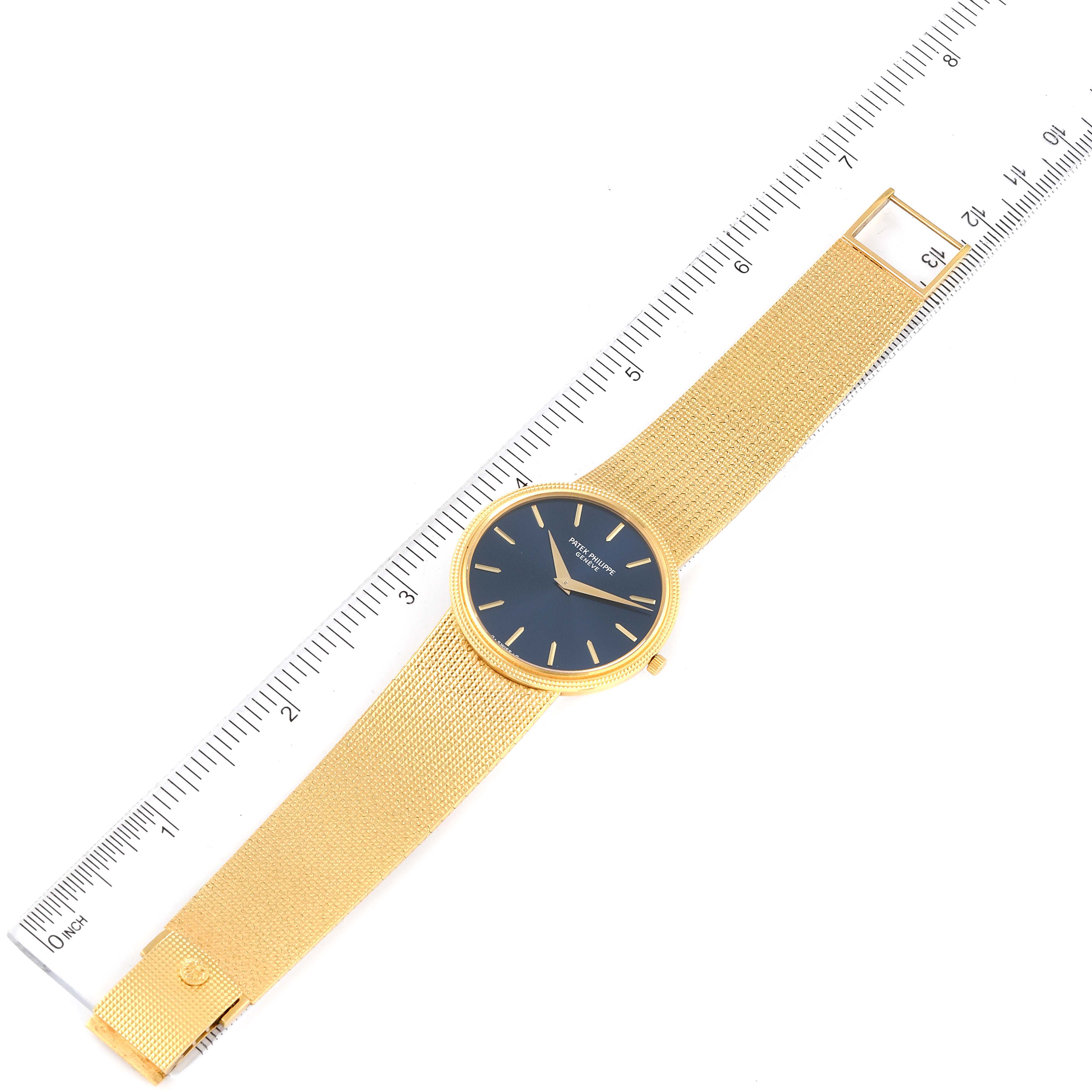 The image shows a Vintage Patek Philippe watch laid flat next to a ruler, displaying its gold bracelet and blue watch face.