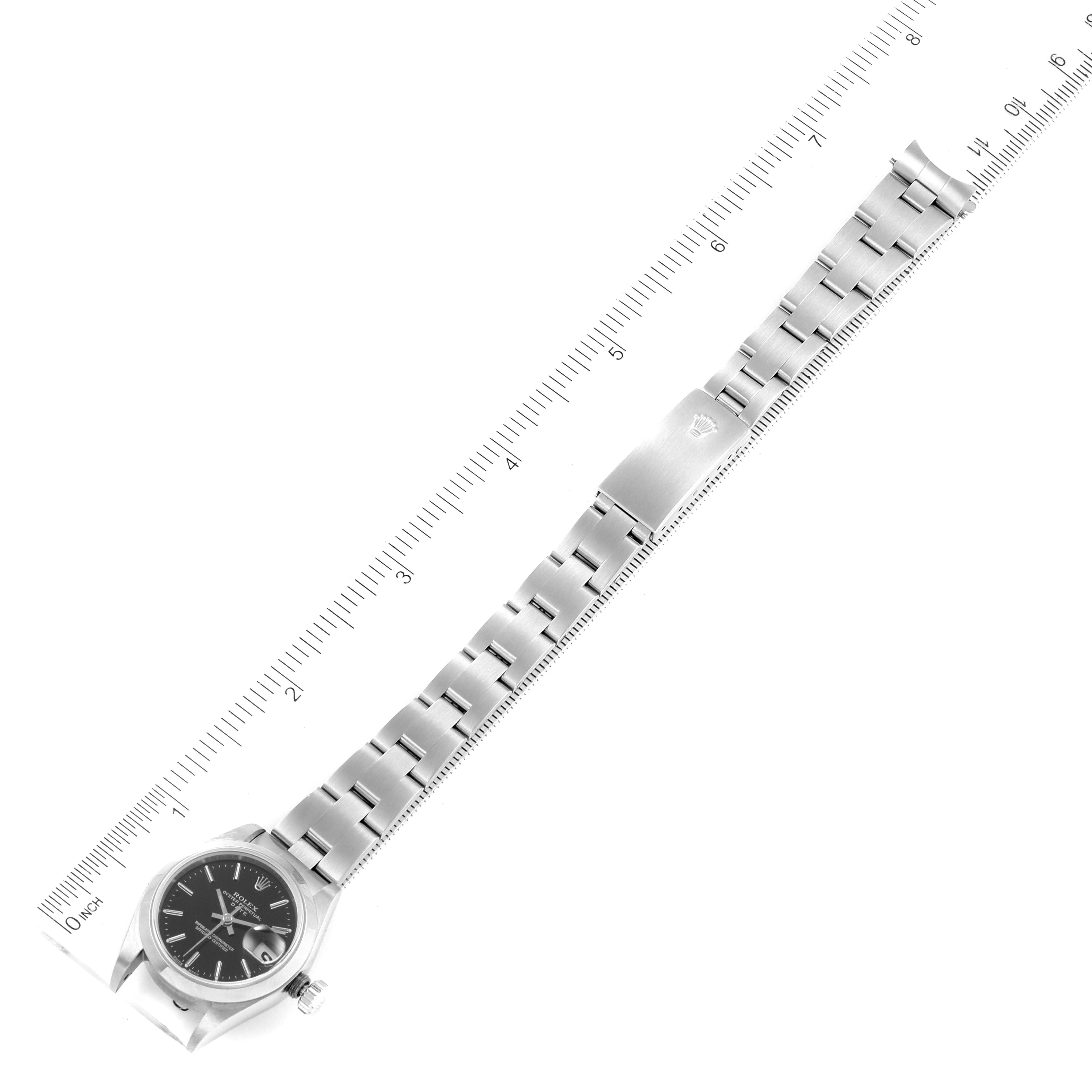 The image shows a top-down view of a Rolex Date 79160 Women
s Stainless Steel Black Dial 79160 Women
s Stainless Steel Black Dial model watch with its bracelet extended next to a ruler for scale.