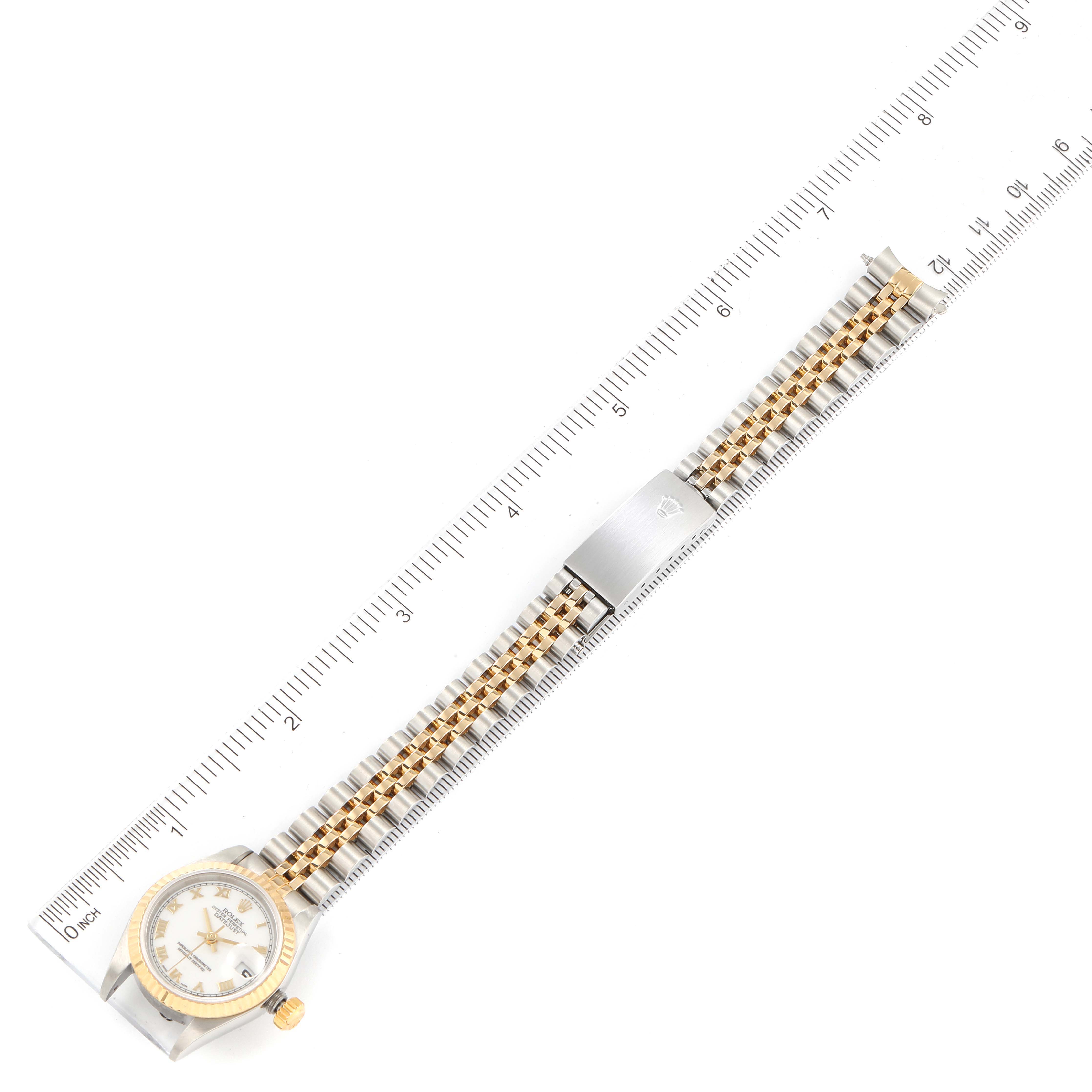 This image shows a top view of a Rolex Datejust 79173 Women's Steel and Gold (two tone) White Dial 79173 Women's Steel and Gold (two tone) White Dial watch with a gold and silver bracelet alongside a ruler for measurement.