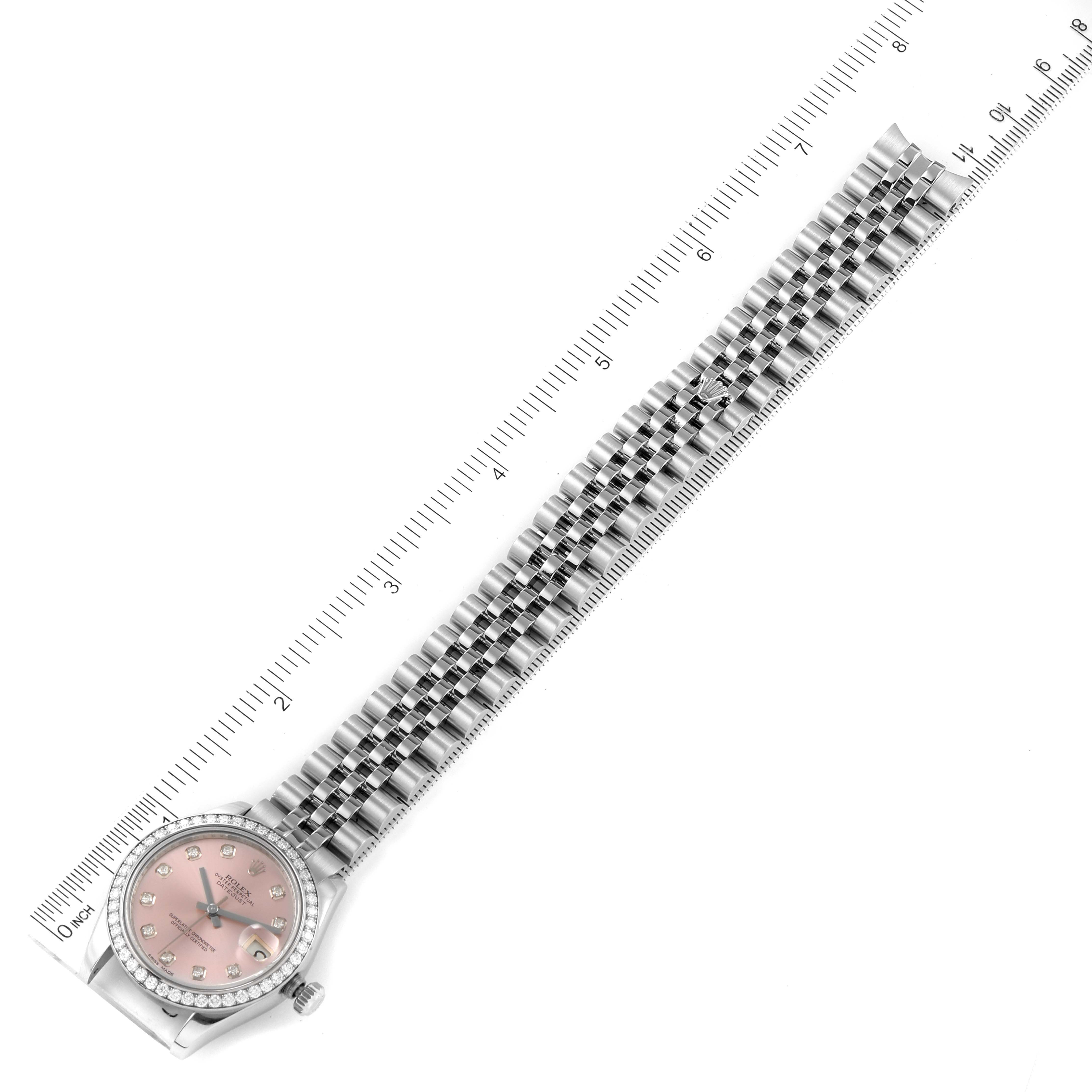 The image shows a Mid-Size Rolex watch with a pink dial and a stainless steel bracelet, displayed flat alongside a ruler.