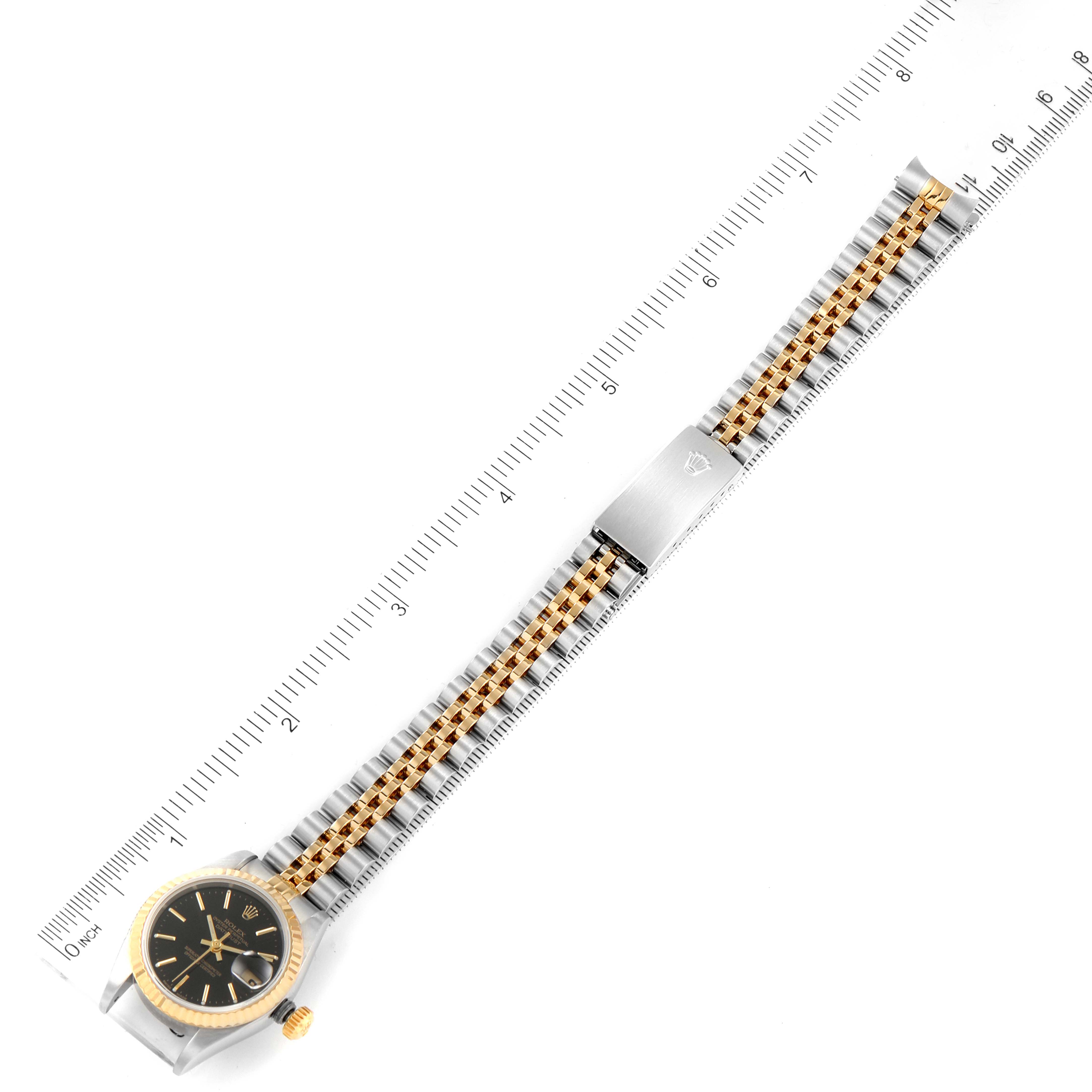 The image shows a top view of the Rolex Datejust 79173 Women's Steel and Gold (two tone) Black Dial 79173 Women's Steel and Gold (two tone) Black Dial watch, including its black dial, bi-color bracelet, and clasp.