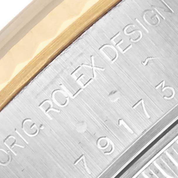 The image shows a close-up of the side of a Rolex Datejust 79173 Women's Steel and Gold (two tone) Blue Dial 79173 Women's Steel and Gold (two tone) Blue Dial, highlighting the engraved Rolex design and serial number.