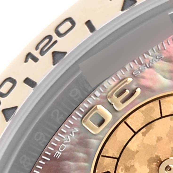 The image shows a close-up of the Rolex Daytona 116503 Men's Steel and Gold (two tone) Mother of Pearl Dial 116503 Men's Steel and Gold (two tone) Mother of Pearl Dial's bezel, part of the dial, and indices at an angled view.