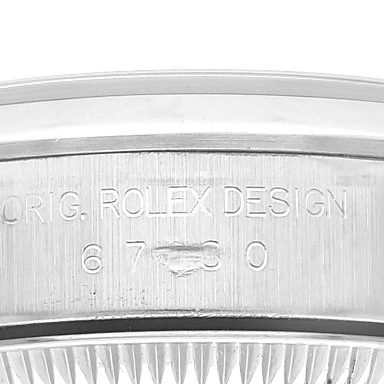 This image shows the engraved case side of a Rolex Oyster Perpetual 67180 Women
s Stainless Steel Blue Dial 67180 Women
s Stainless Steel Blue Dial watch, displaying its design and model number.