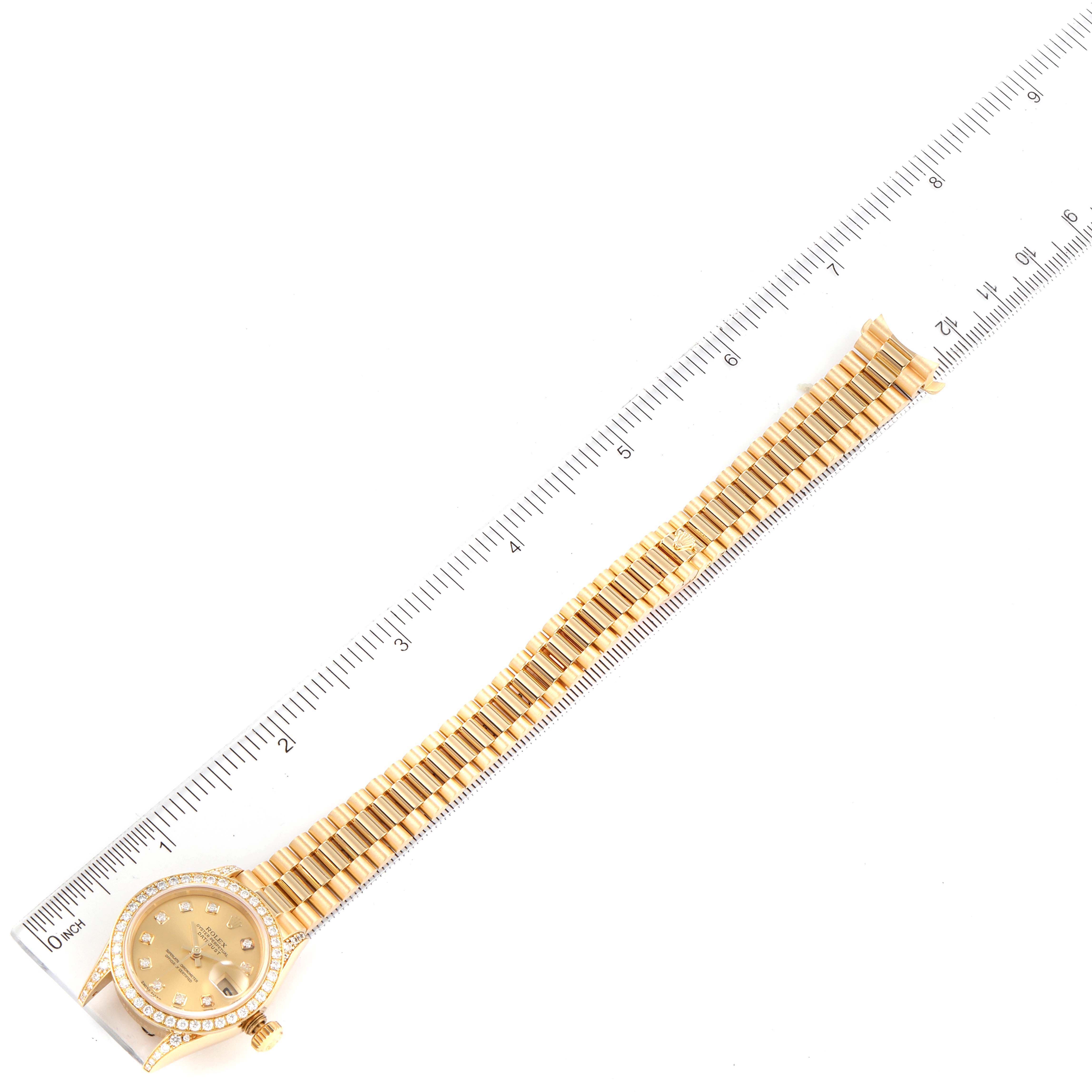 The Rolex President 79158 Women
s Yellow Gold Champagne Dial 79158 Women
s Yellow Gold Champagne Dial model watch is shown flat with its band fully extended next to a ruler for measurement.