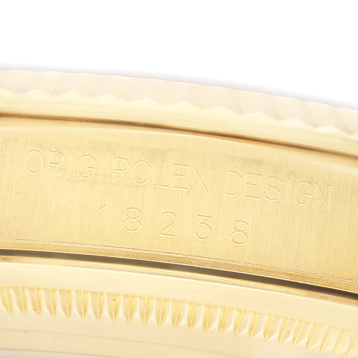 The image shows a close-up of the side of a gold Rolex GMT-Master 18238 Men's Yellow Gold Champagne Dial, displaying engravings and part of the bezel.