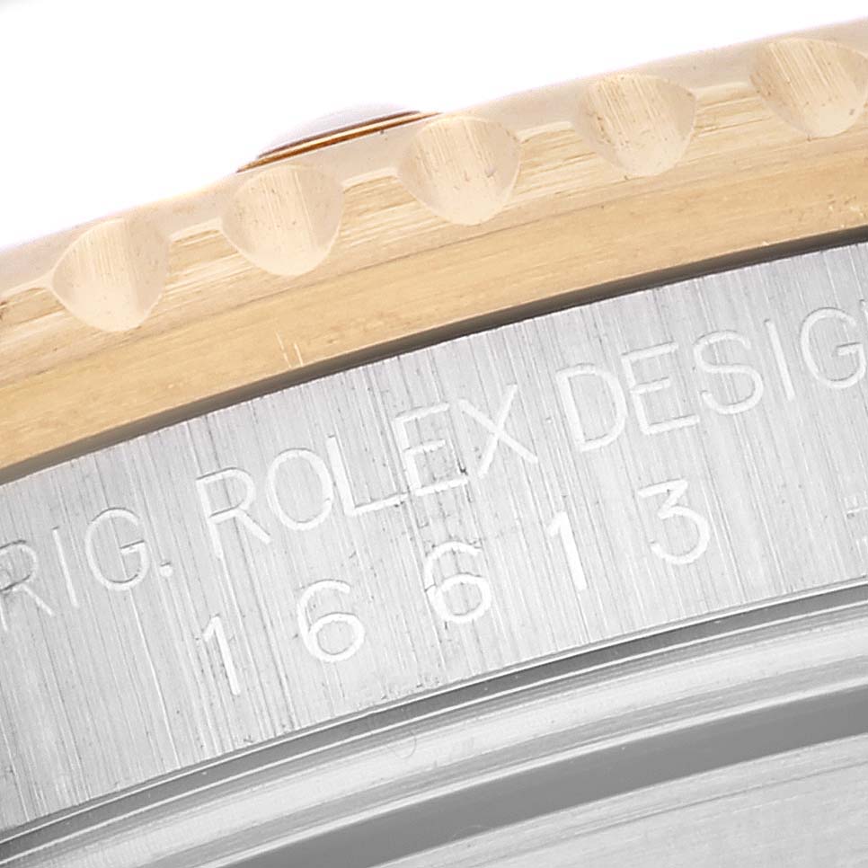 The image shows a close-up of the engraved text on the side of the case and the bezel of a Rolex Submariner 16613 Men
s Steel and Gold (two tone) Black Dial 16613 Men
s Steel and Gold (two tone) Black Dial watch.