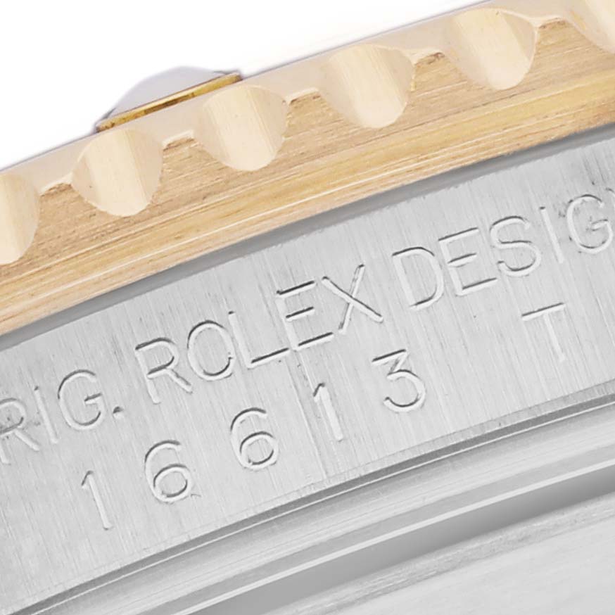 The image shows a close-up of the Rolex Submariner 16613 Men's Steel and Gold (two tone) Silver Dial 16613 Men's Steel and Gold (two tone) Silver Dial's engraved case side and part of the bezel, highlighting model details.