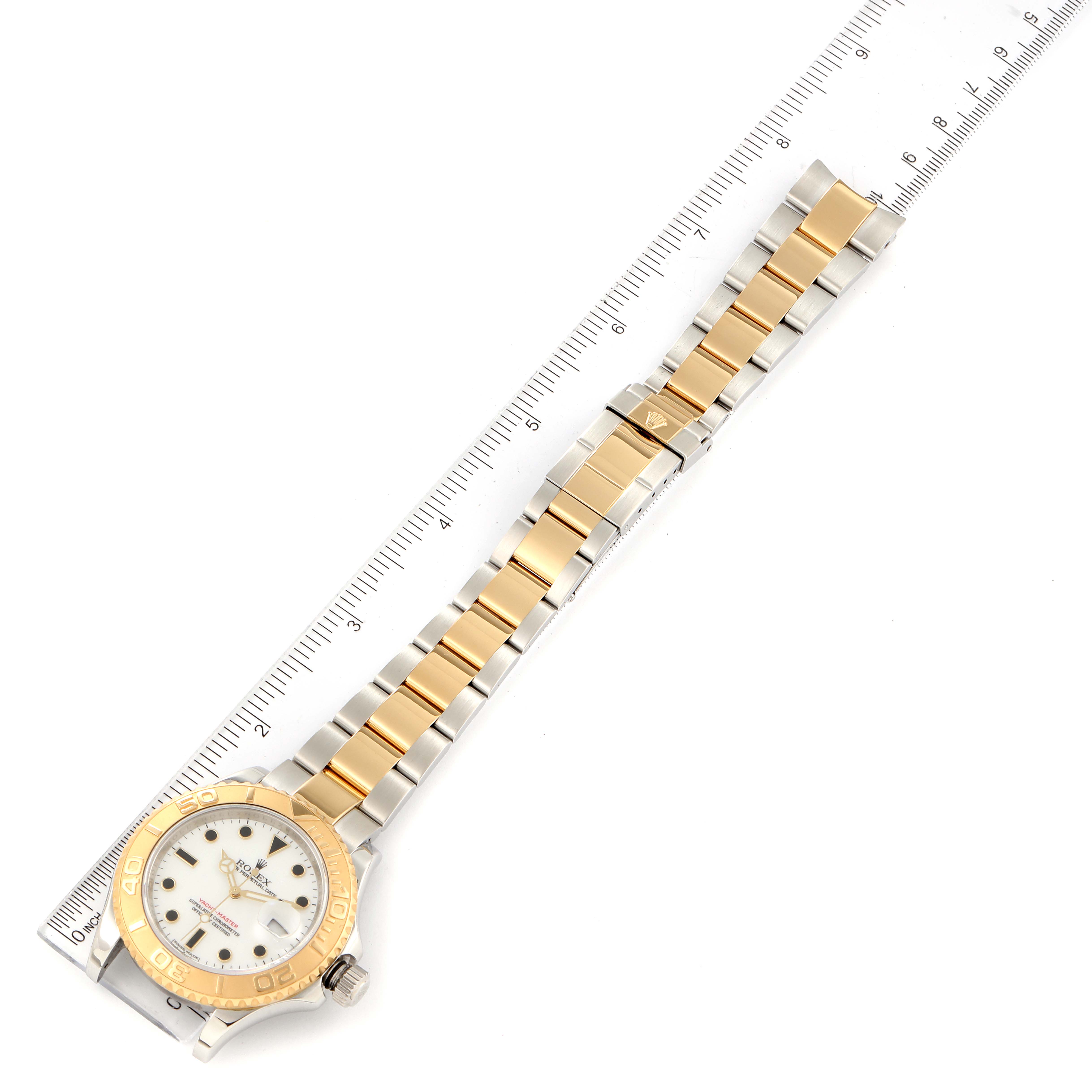 The image shows a Rolex Yacht-Master 16623 Men
s Steel and Gold (two tone) White Dial 16623 Men
s Steel and Gold (two tone) White Dial watch laid flat with its gold and silver bracelet aligned with a ruler.