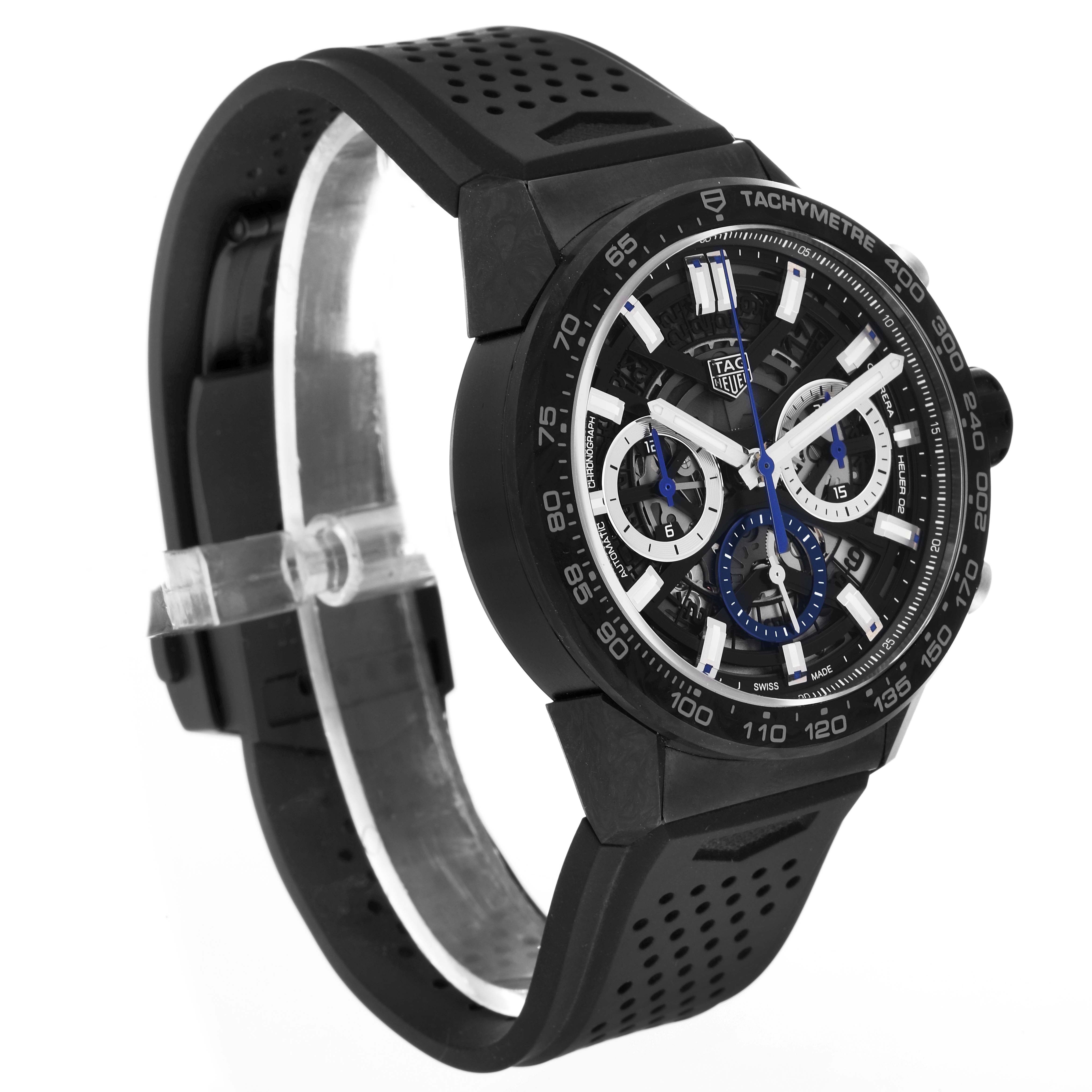 The Tag Heuer Carrera watch is shown at a three-quarter angle, highlighting its black strap, tachymeter bezel, and intricate dial.