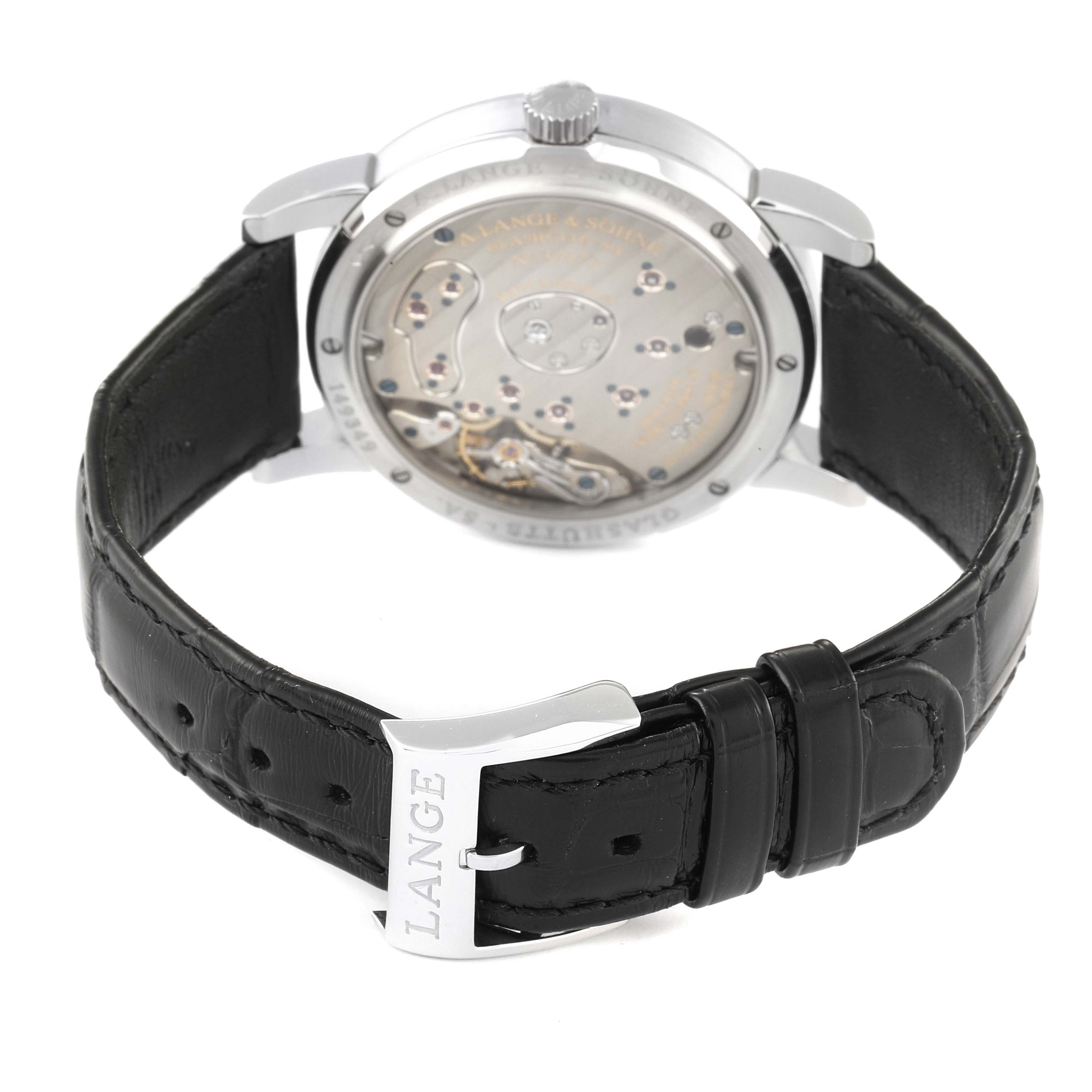 The image shows the back view of the A. Lange & Sohne Lange 1 109.025 Men's Platinum Silver Dial watch, highlighting the movement and black leather strap with a "LANGE" engraved buckle.