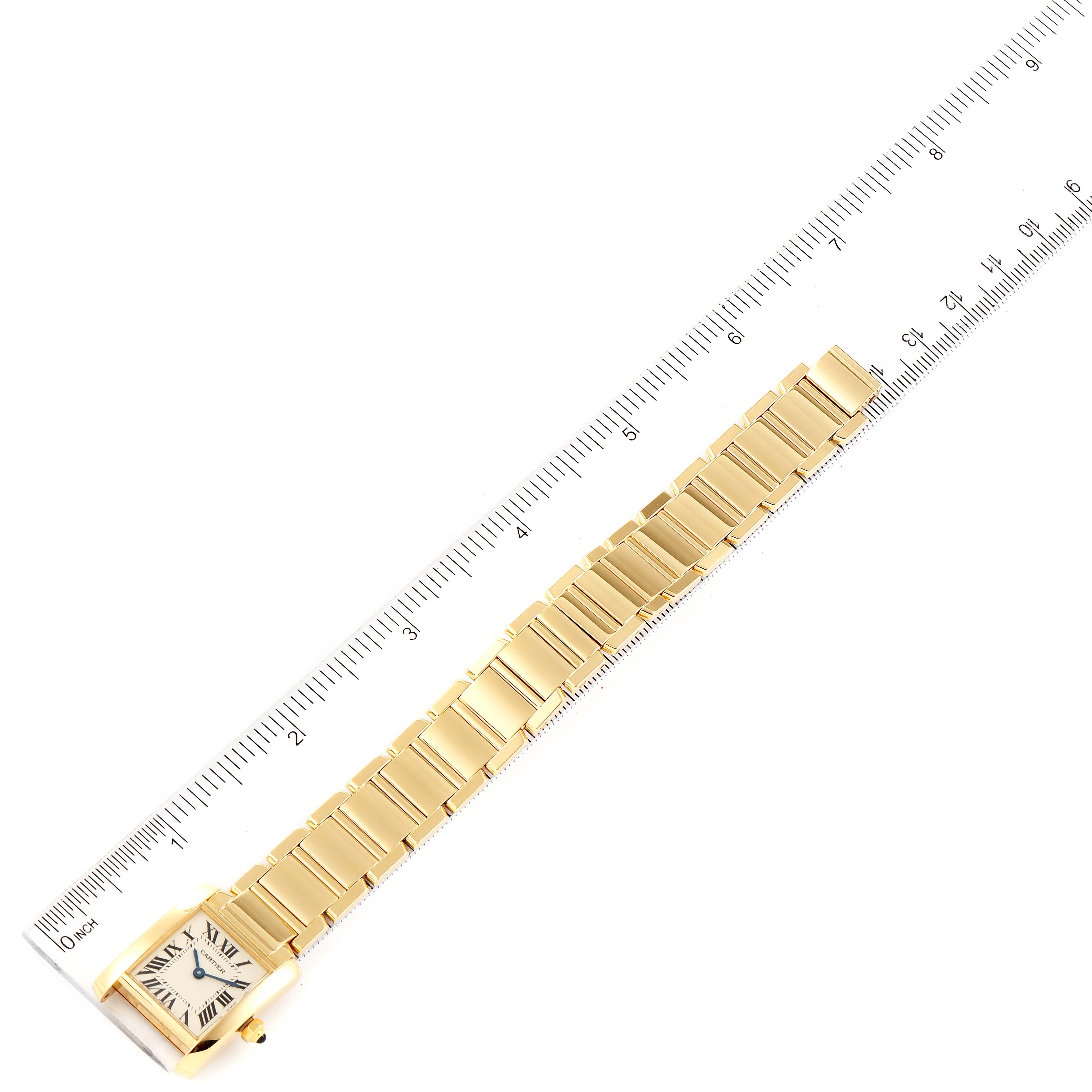 The Cartier Tank Francaise W50002N2 Women
s Yellow Gold Silver Dial W50002N2 Women
s Yellow Gold Silver Dial watch is shown flat, highlighting the gold bracelet and face, alongside a ruler for scale.