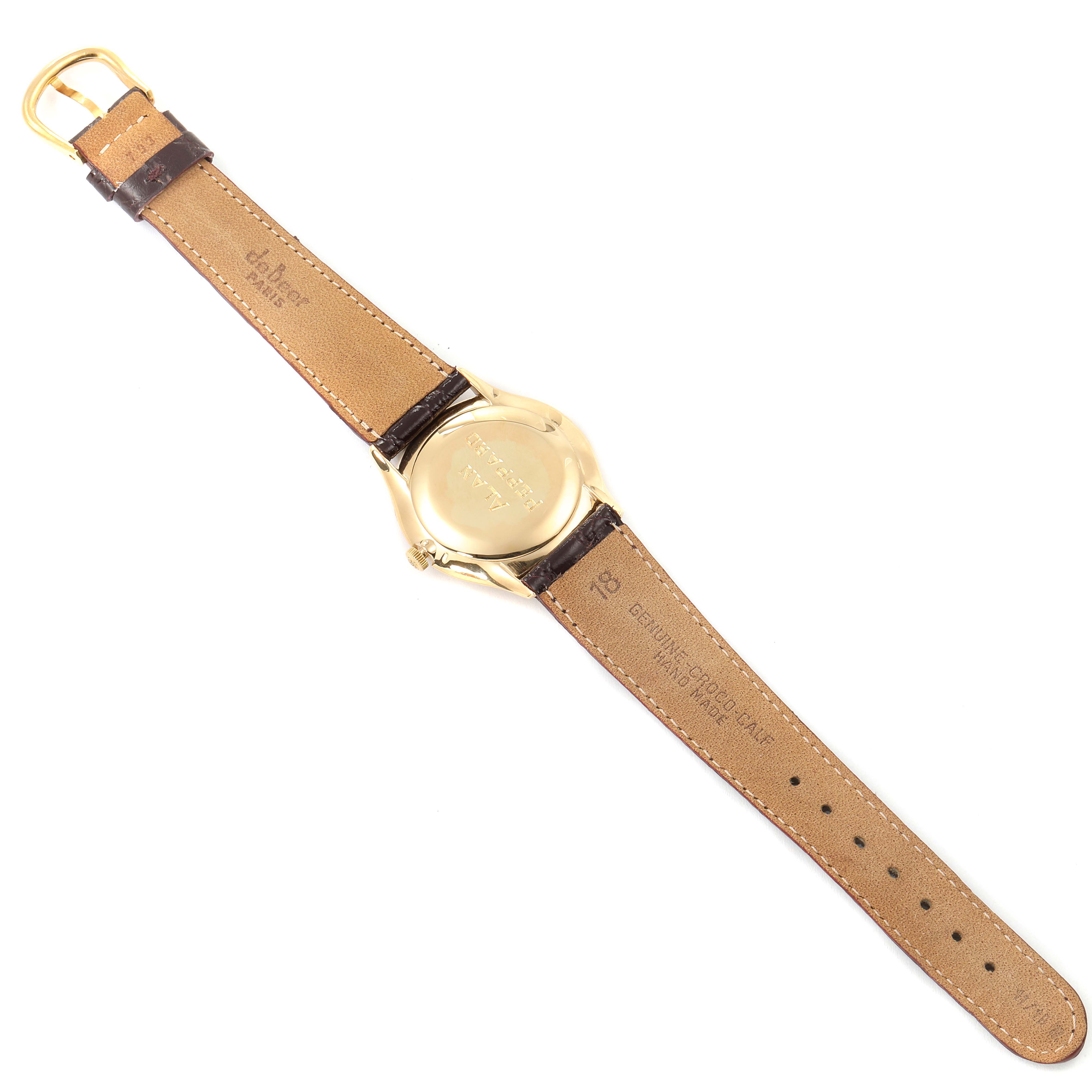 This is a top-down view of the back of a Vintage Patek Philippe watch showing its leather strap and gold case back.