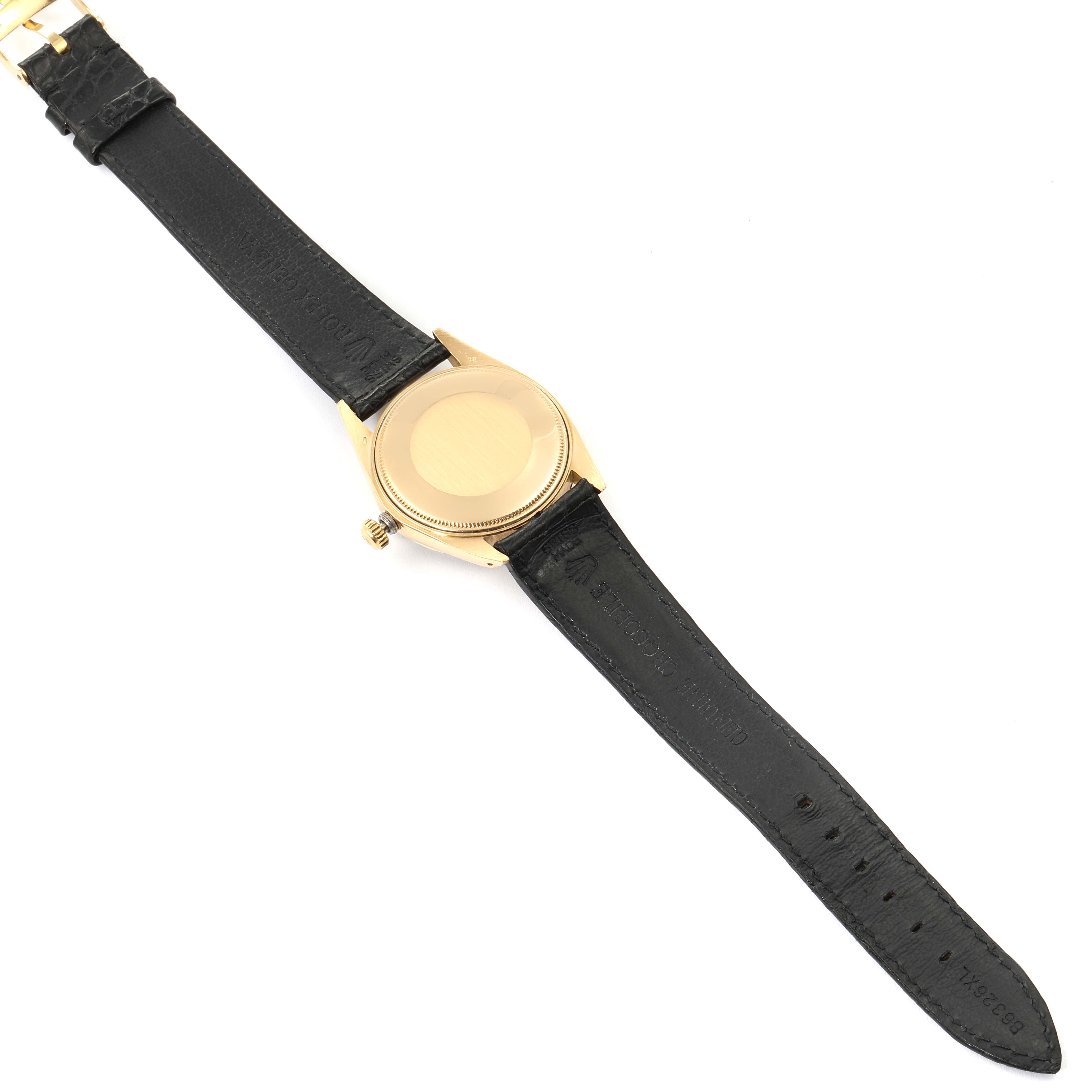 The image shows the back of a Vintage Collection Rolex watch with a black leather strap and gold case, viewed from a top-down angle.