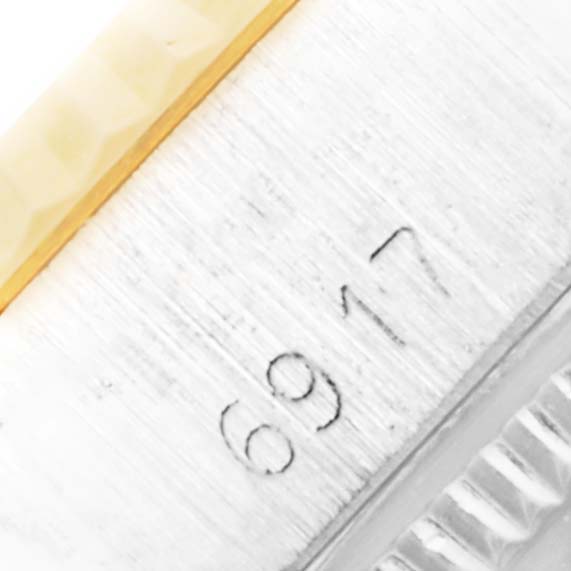 The close-up image shows part of the serial number and the edge of the bezel of a Rolex Date 6917 Women's Steel and Gold (two tone) Champagne Dial 6917 Women's Steel and Gold (two tone) Champagne Dial model watch.