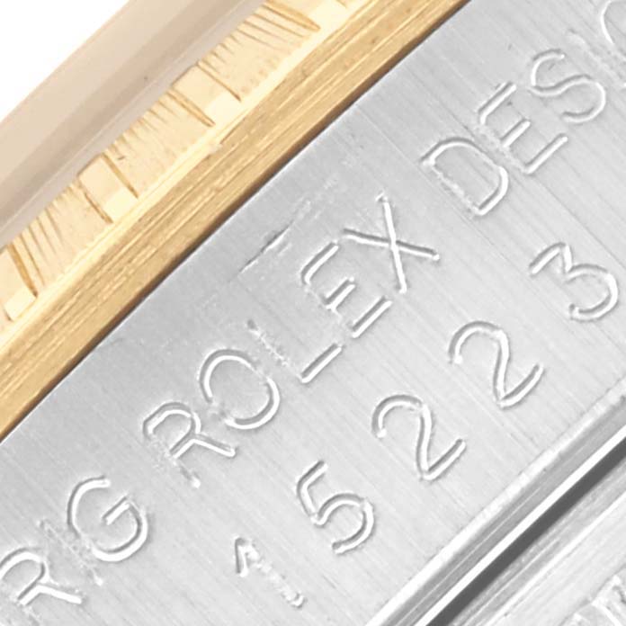 The image shows a close-up of the side of a Rolex Date 15223 Men's Steel and Gold (two tone) Silver Dial 15223 Men's Steel and Gold (two tone) Silver Dial model, displaying part of the engraving on the watch case.