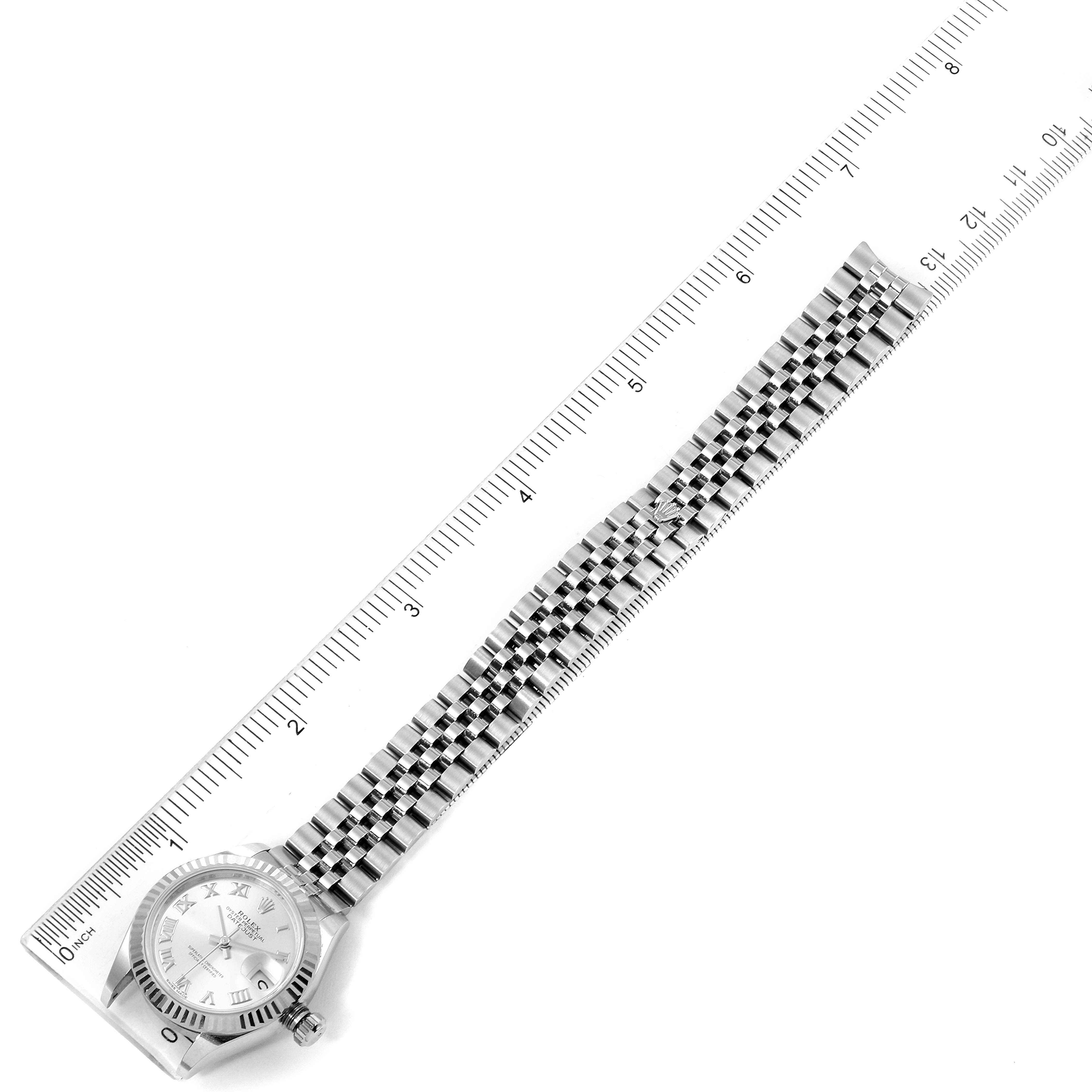 This image shows a top view of a Rolex Datejust 279174 Women's Stainless Steel Silver Dial 279174 Women's Stainless Steel Silver Dial watch with a full view of its face and bracelet lying alongside a ruler.
