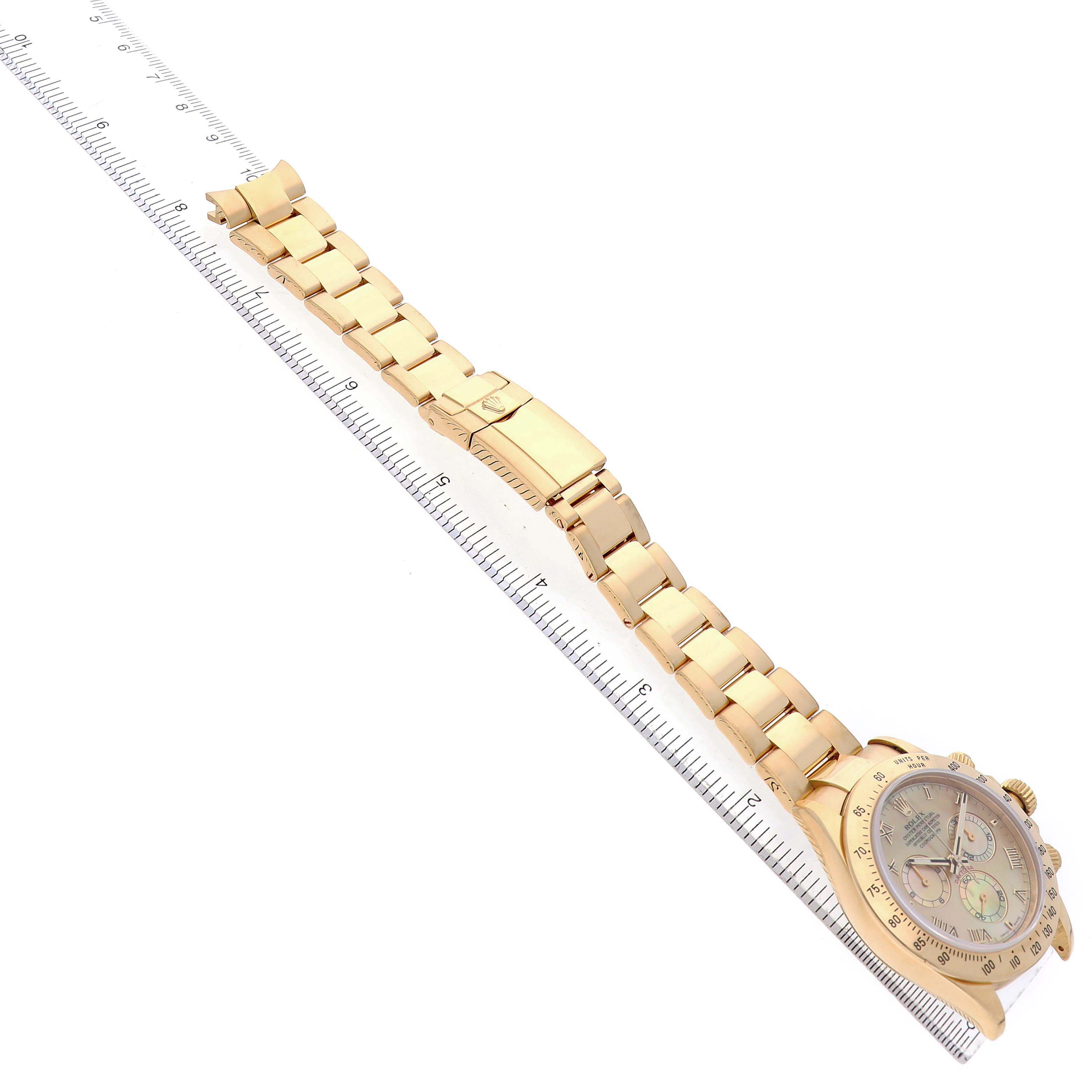 The image shows a top view of a Rolex Daytona 116528 Men's Yellow Gold Mother of Pearl Dial watch, highlighting its gold bracelet and clasp alongside a ruler.