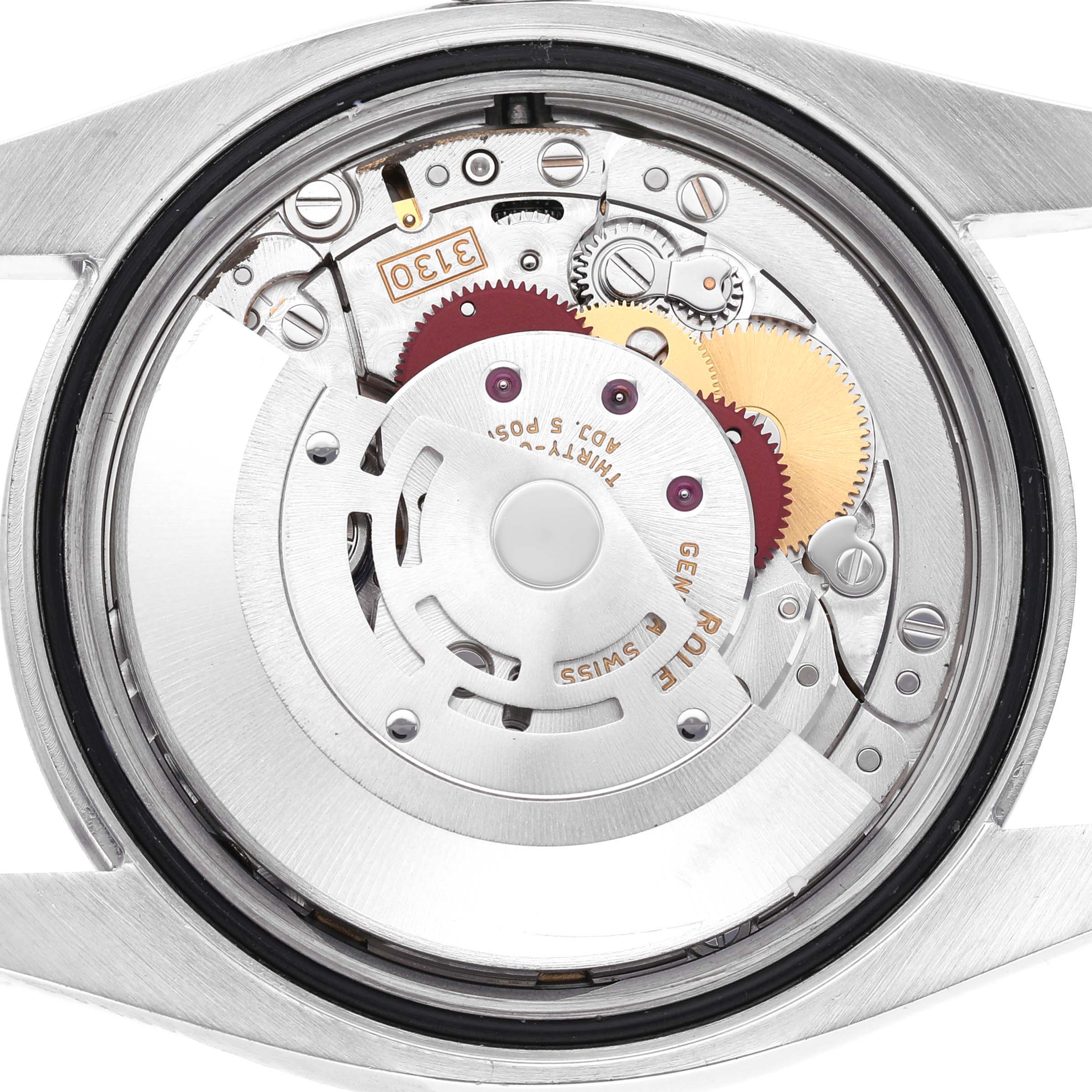 The image shows the inner mechanism and movement of the Rolex Oyster Perpetual 116000 Men's Stainless Steel Blue Dial watch, with gears and components visible from the back.