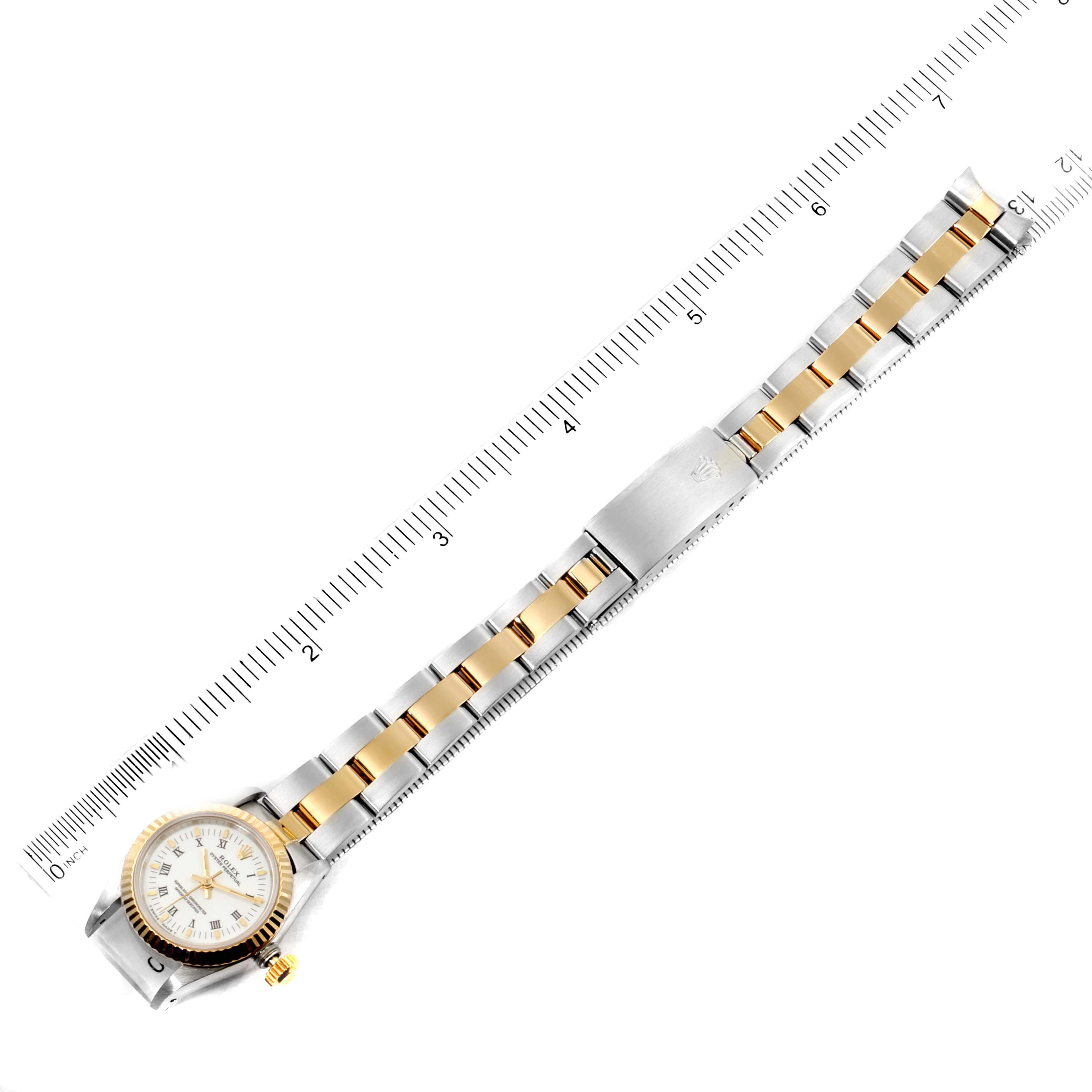 The image shows an overhead view of a Rolex Oyster Perpetual 67193 Women's Steel and Gold (two tone) White Dial 67193 Women's Steel and Gold (two tone) White Dial watch and its bracelet alongside a measuring ruler.