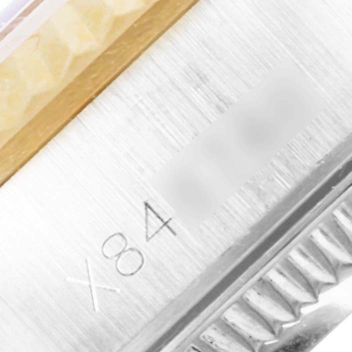 This close-up image of a Rolex Oyster Perpetual 67193 Women's Steel and Gold (two tone) White Dial 67193 Women's Steel and Gold (two tone) White Dial model shows details of its bezel, part of the bracelet, and some engraved numbers.