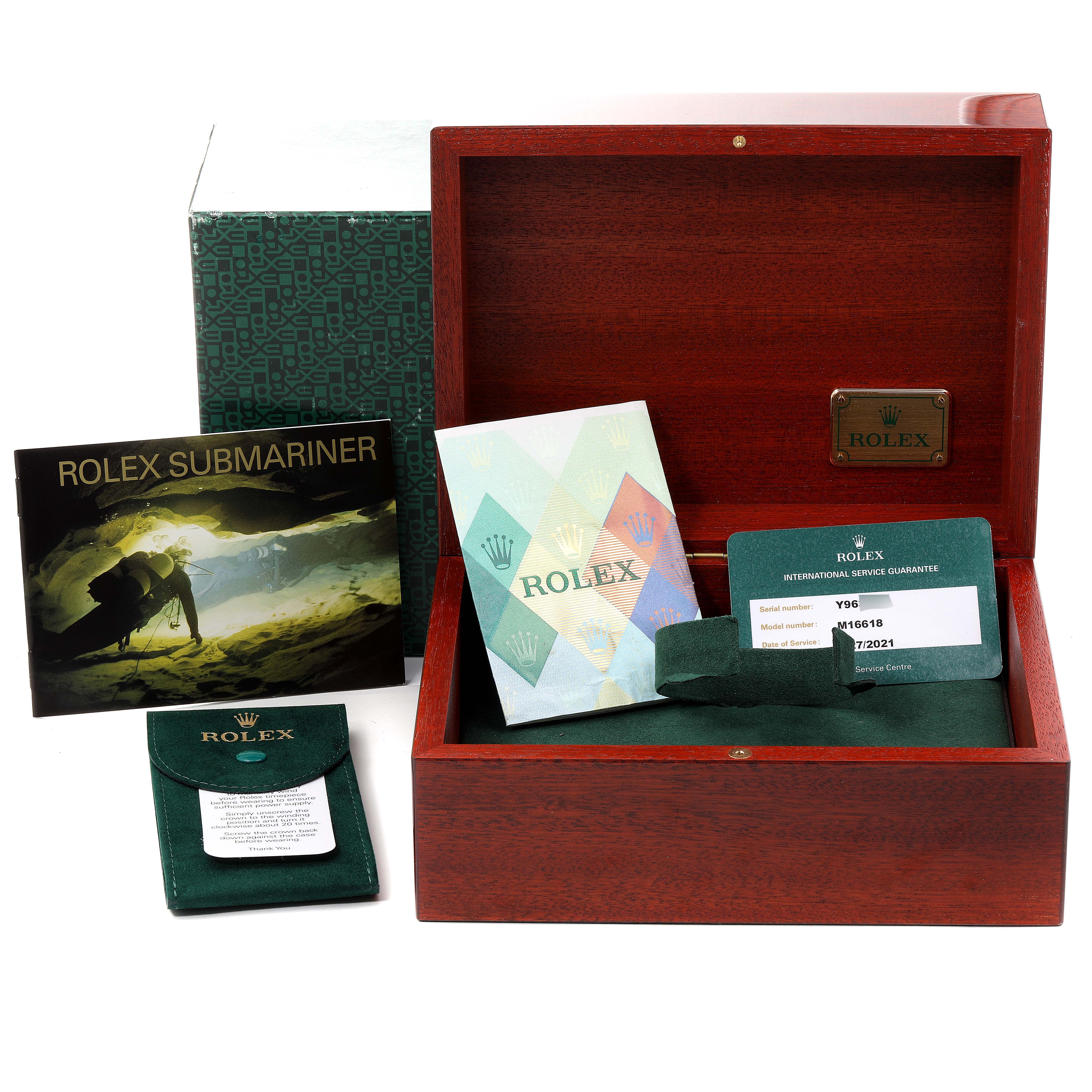 The image shows a Rolex Submariner 16618 Men
s Yellow Gold Blue Dial 16618 Men
s Yellow Gold Blue Dial watch box, service booklet, warranty card, and accessories from a frontal angle.