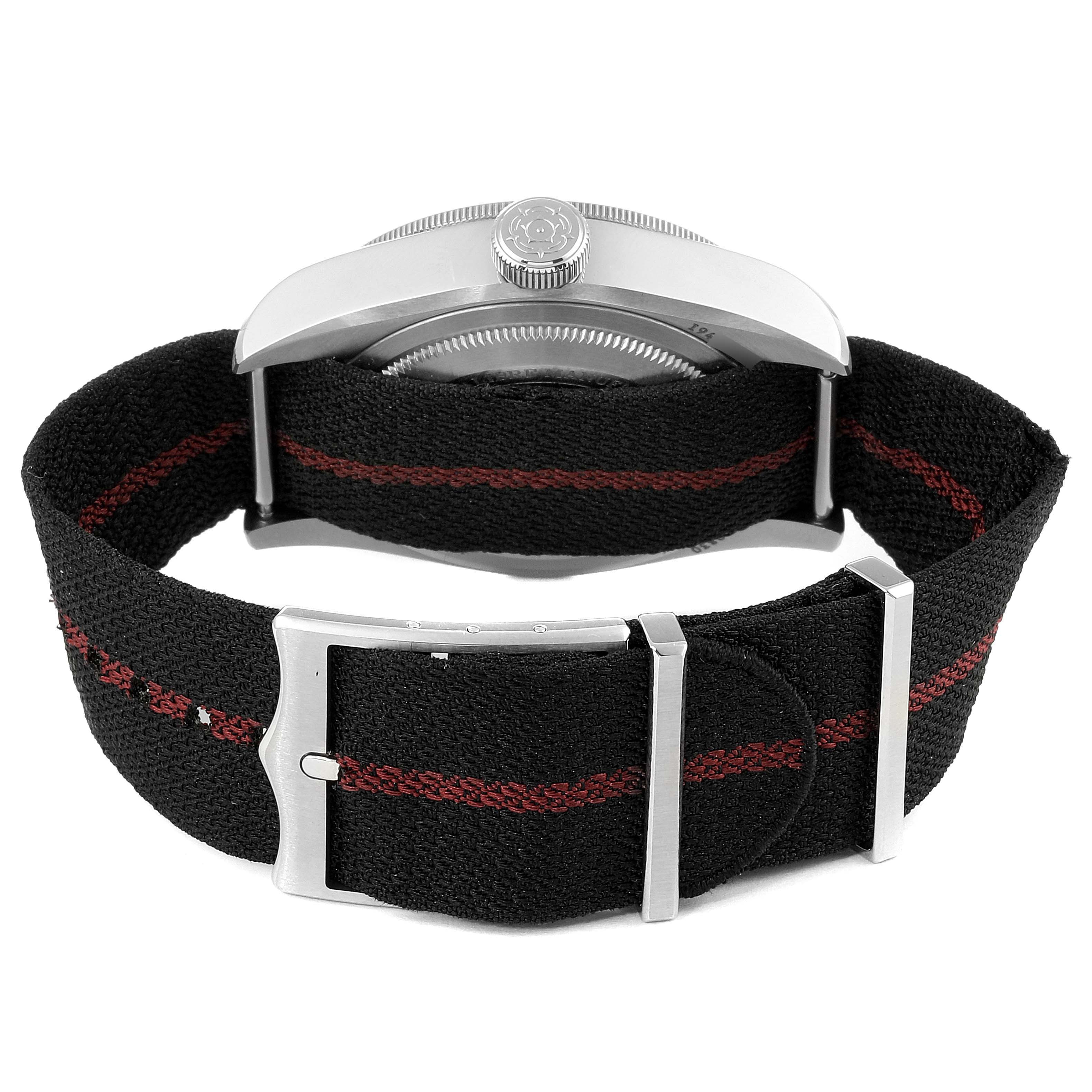 The image shows the rear view of the Tudor Heritage Black Bay 79830RB Men's Stainless Steel Black Dial 79830RB Men's Stainless Steel Black Dial watch, focusing on its black fabric strap with a red stripe and metal buckle.