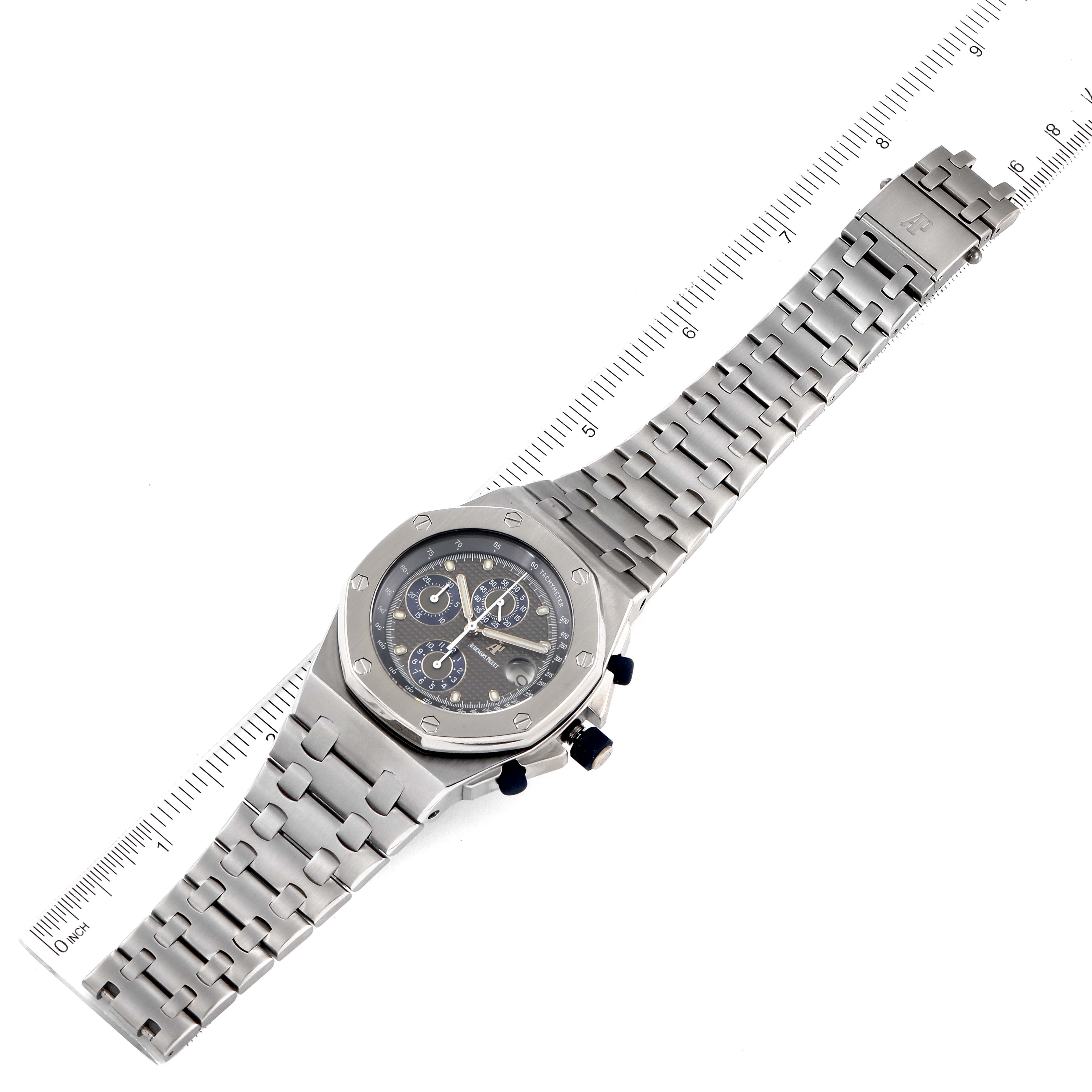 The image shows an angled top view of an Audemars Piguet Royal Oak Offshore 25721TI.O.1000TI.01 Men's Titanium Grey Dial 25721TI.O.1000TI.01 Men's Titanium Grey Dial watch, displaying the face, bezel, and metal bracelet with a ruler for scale.