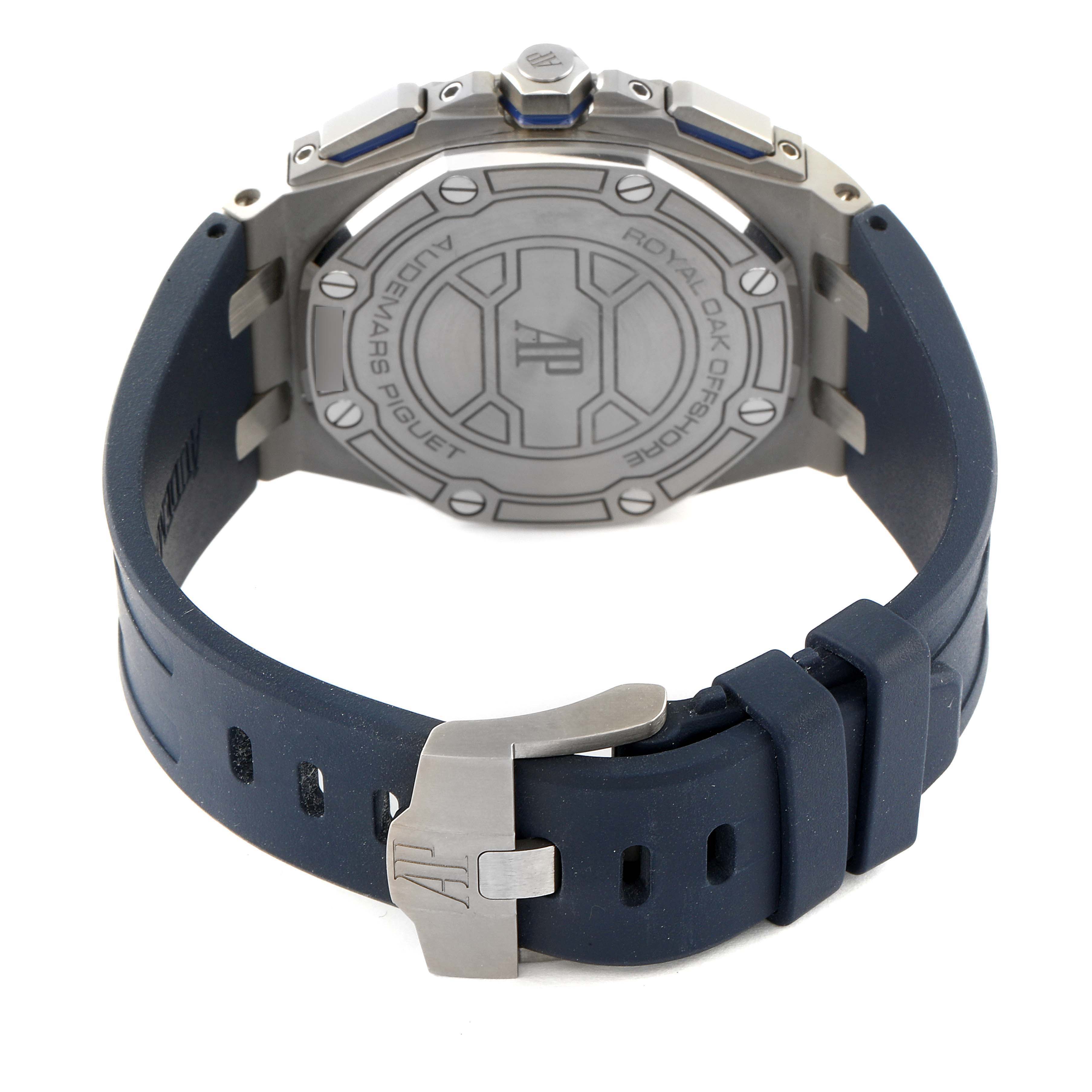 The image shows the back and clasp of an Audemars Piguet Royal Oak Offshore 26480TI.OO.A027CA.01 Men's Titanium Blue Dial 26480TI.OO.A027CA.01 Men's Titanium Blue Dial watch, featuring a metal case with an AP logo on the case back and a blue strap.