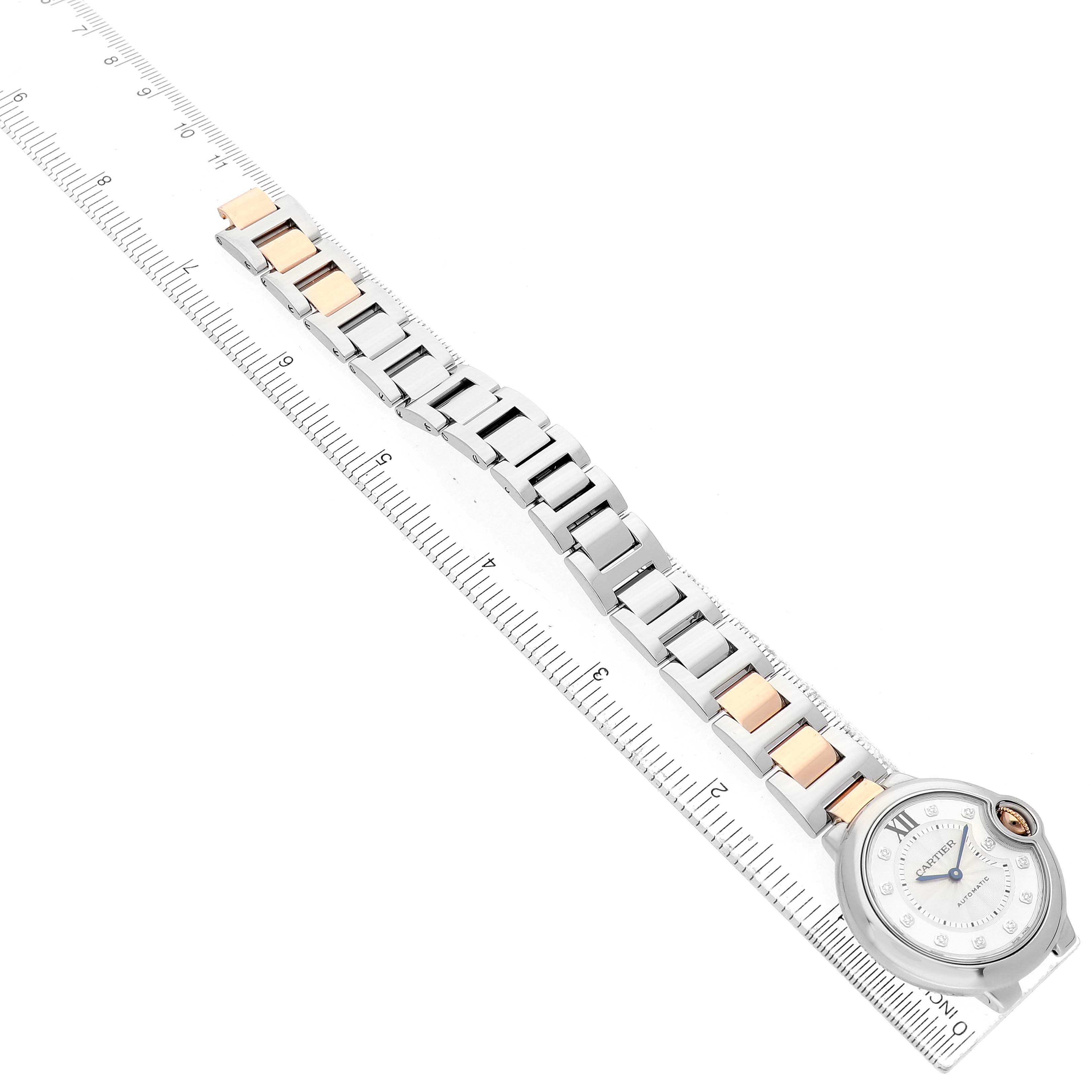 The Cartier Ballon Bleu WE902044 Women's Steel and Gold (two tone) Silver Dial watch is shown from a top-down angle, displaying the face and full metal bracelet on a ruler.