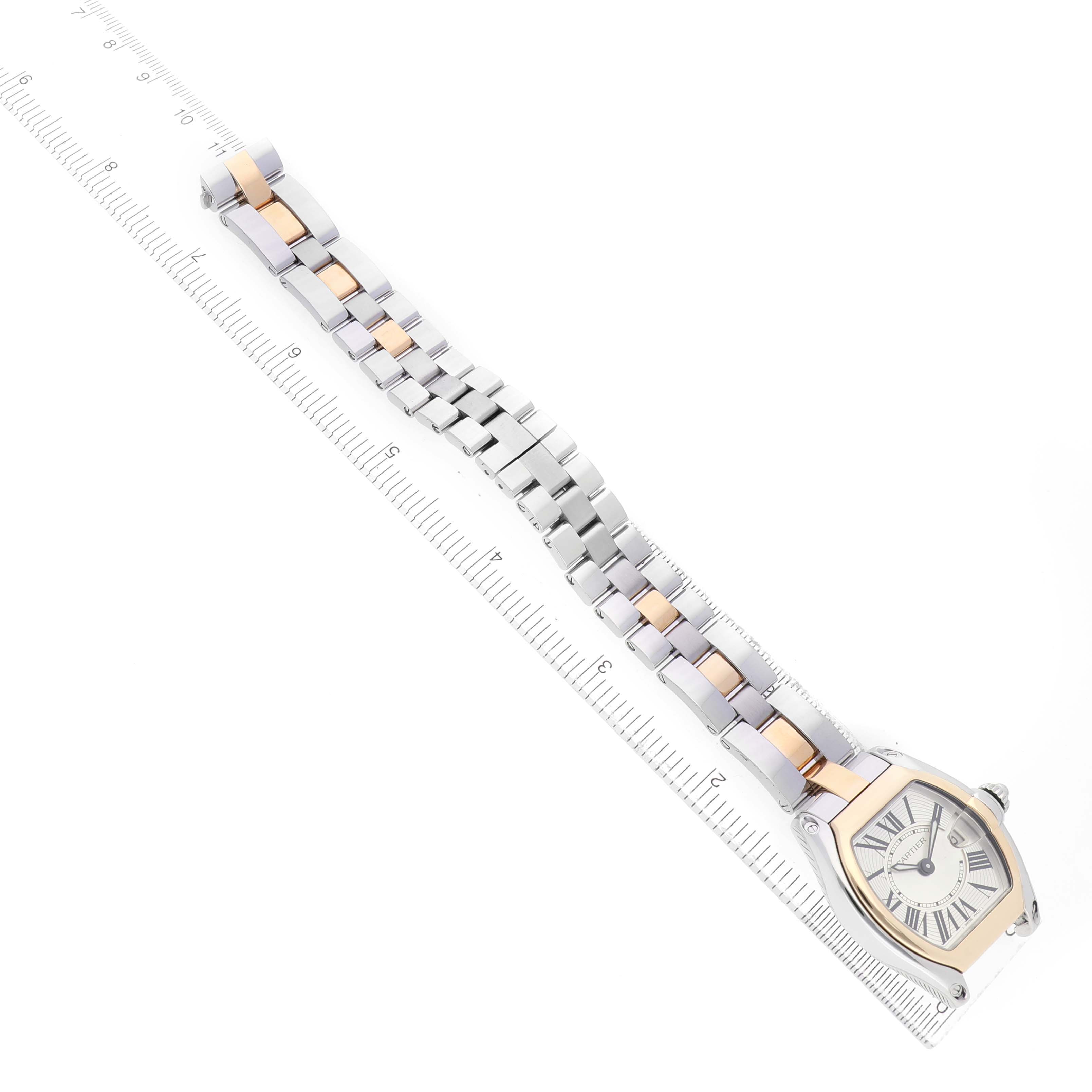 The Cartier Roadster W62026Y4 Women's Steel and Gold (two tone) Transparent Dial watch is shown at an angle highlighting the face and metal bracelet with a dual-tone design alongside a ruler.