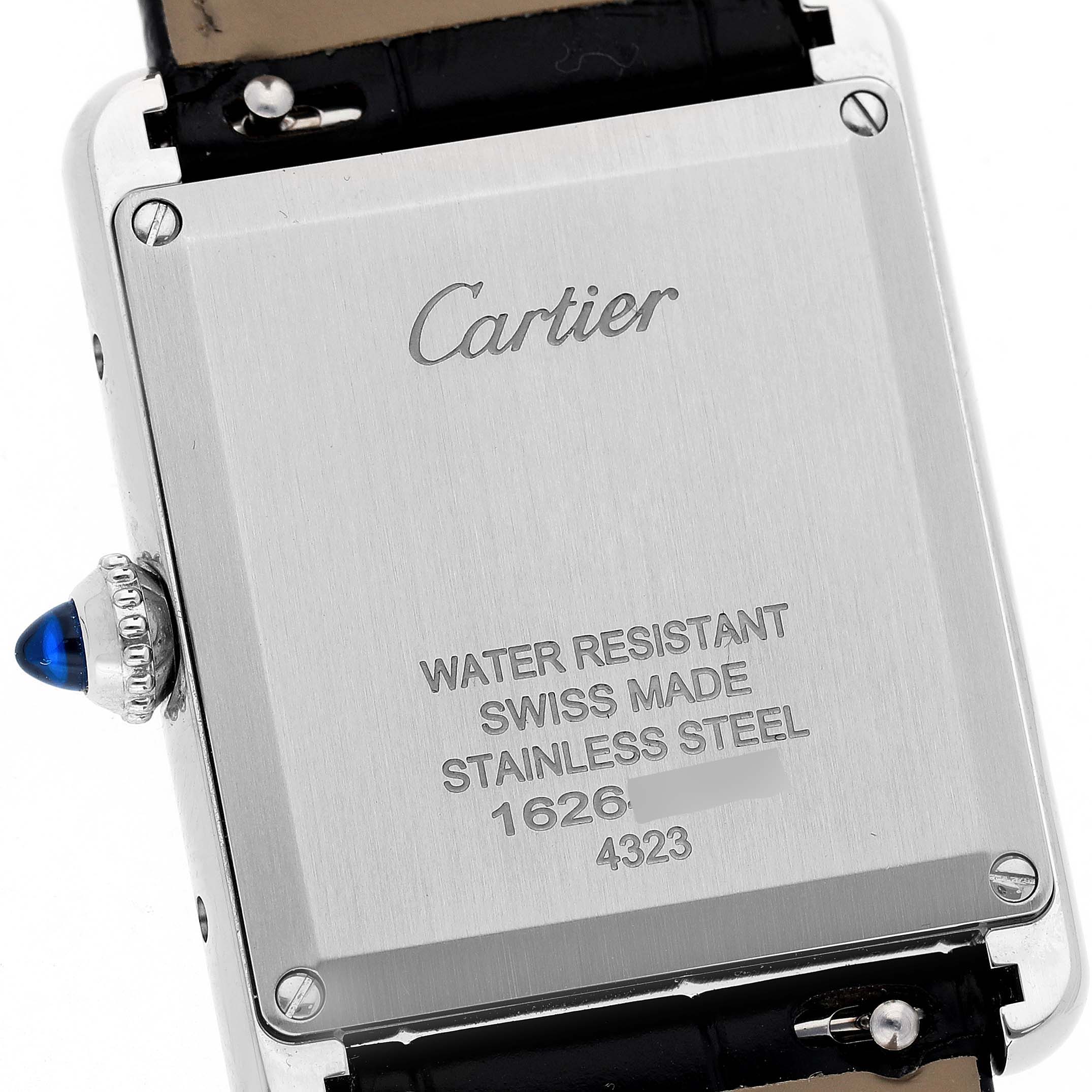 The image shows the back case of a Cartier Tank Must WSTA0072 Women's Stainless Steel Black Dial watch, highlighting the brand engraving, screws, and crown with a blue cabochon.