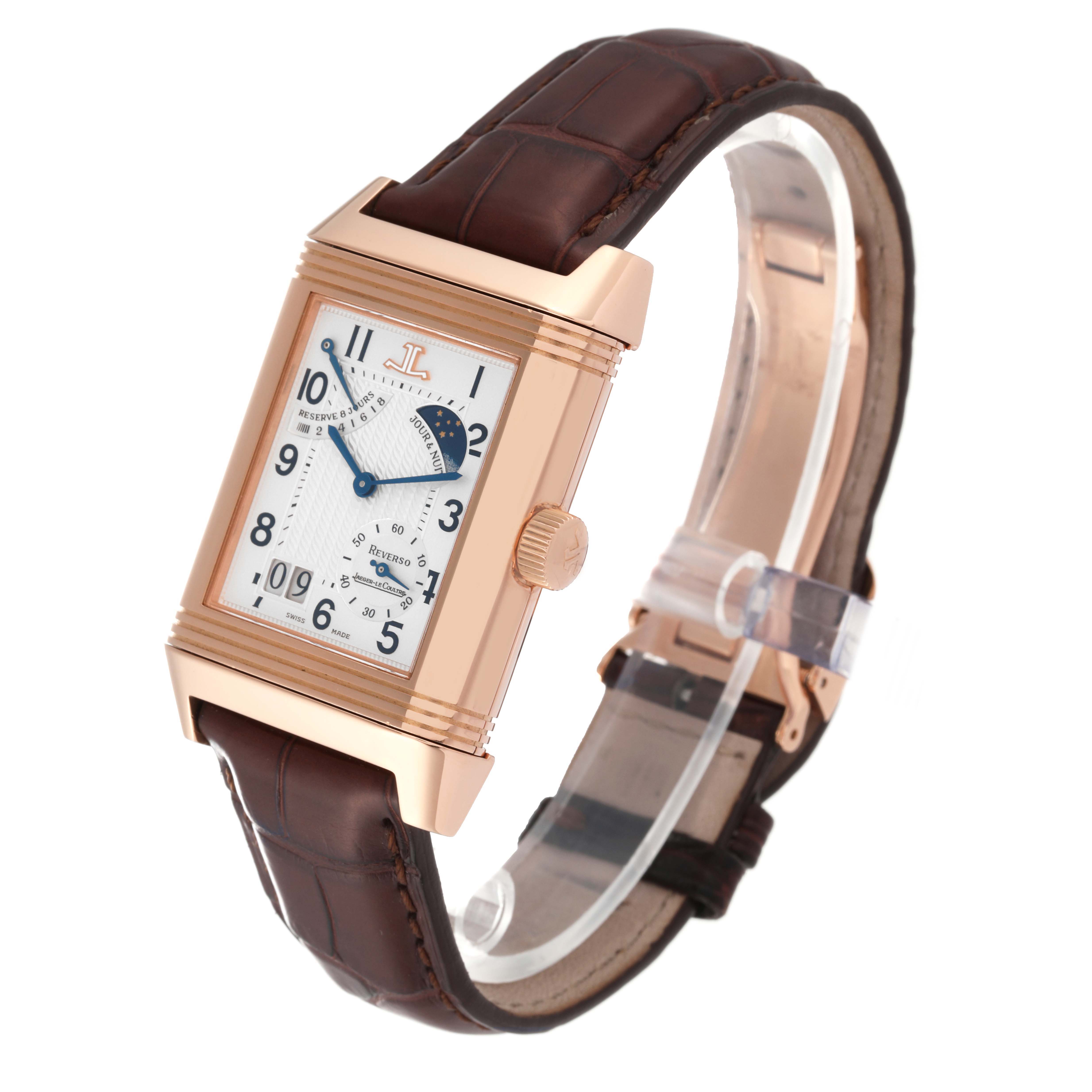 The Jaeger-LeCoultre Reverso watch is shown at a three-quarter angle, displaying its rectangular face, crown, and brown leather strap.