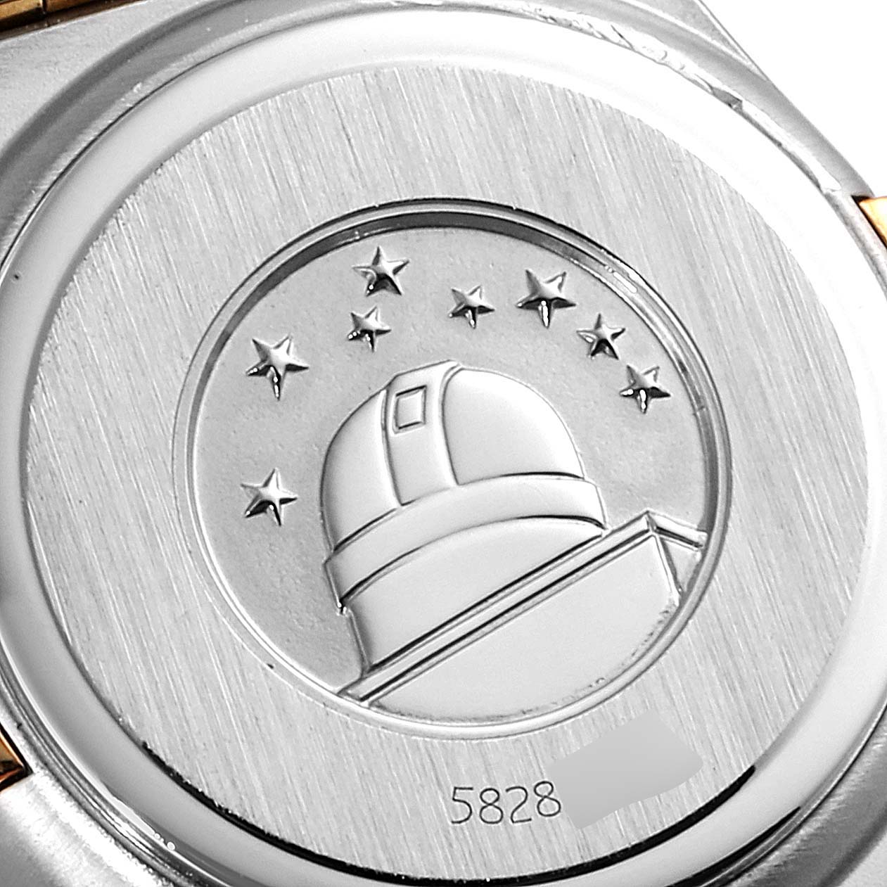 This image shows the case back of an Omega 1267.75.00 Women's Steel and Gold (two tone) Mother of Pearl Dial 1267.75.00 Women's Steel and Gold (two tone) Mother of Pearl Dial Constellation 95 Mother of Pearl Diamond Watch 1267.75.00, featuring an observatory emblem and stars.