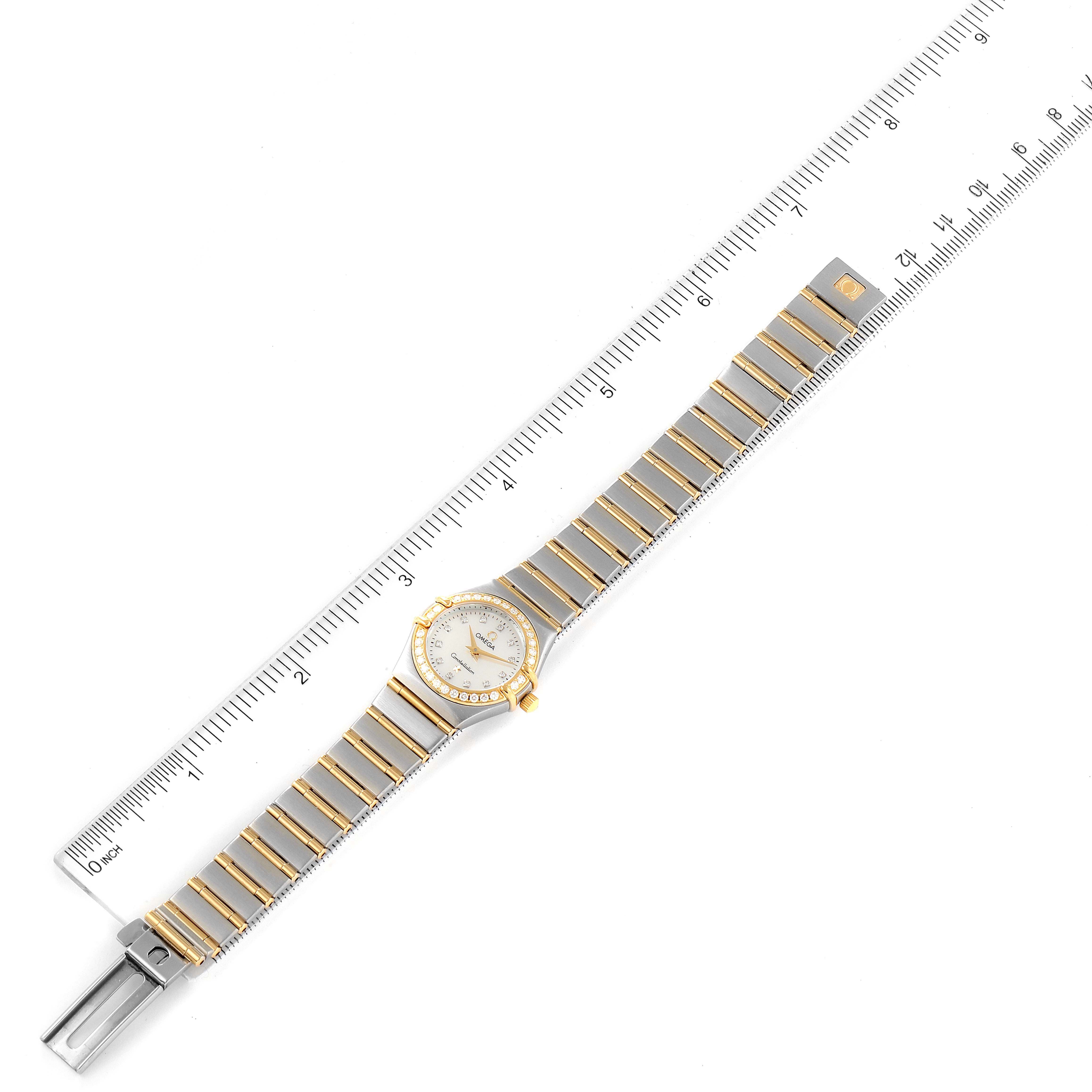 The Omega 1267.75.00 Women's Steel and Gold (two tone) Mother of Pearl Dial 1267.75.00 Women's Steel and Gold (two tone) Mother of Pearl Dial Constellation 95 Mother of Pearl Diamond Watch 1267.75.00 is shown flat, displaying the dial, bezel, and bracelet against a ruler.