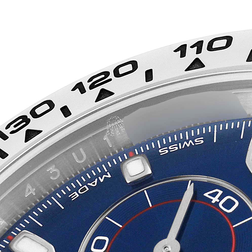 The image shows a close-up of the bezel and a portion of the dial of a Rolex Daytona 116509 Men's White Gold Blue Dial 116509 Men's White Gold Blue Dial watch, highlighting its tachymeter scale and markers.