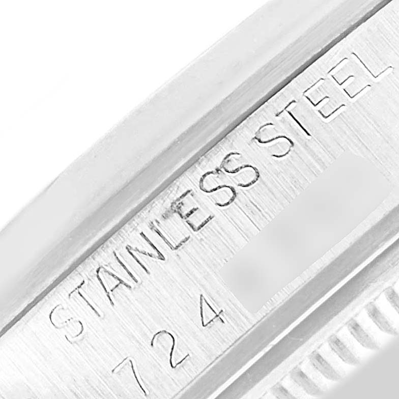 This image shows a close-up of the Rolex Date 15000 Men's Stainless Steel Silver Dial 15000 Men's Stainless Steel Silver Dial model watch case with engraved text "STAINLESS STEEL" and a partially visible serial number.
