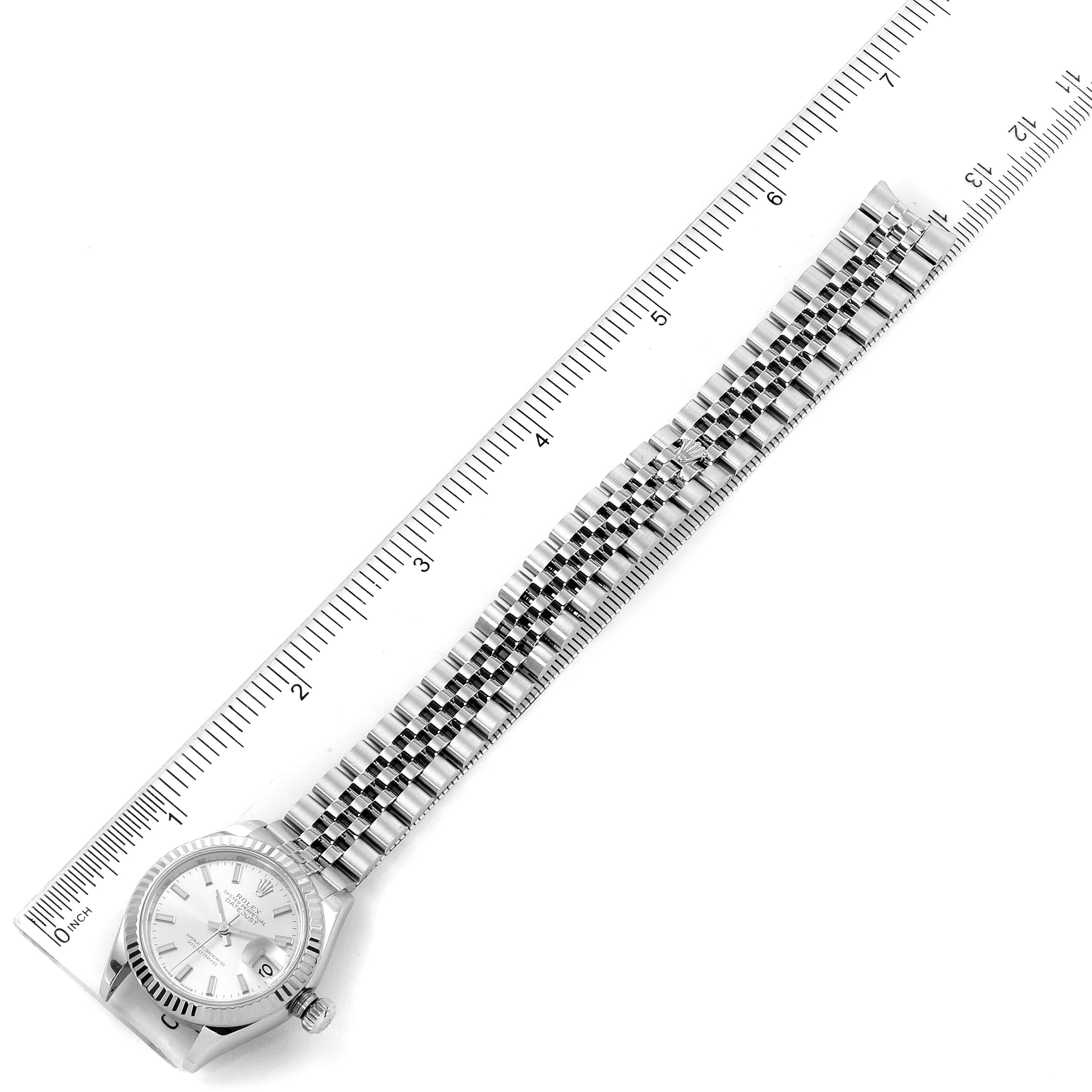 The image shows a Rolex Datejust 279174 Women
s Stainless Steel Silver Dial 279174 Women
s Stainless Steel Silver Dial watch from a top-down angle, displaying the face, bezel, and bracelet alongside a ruler for scale.