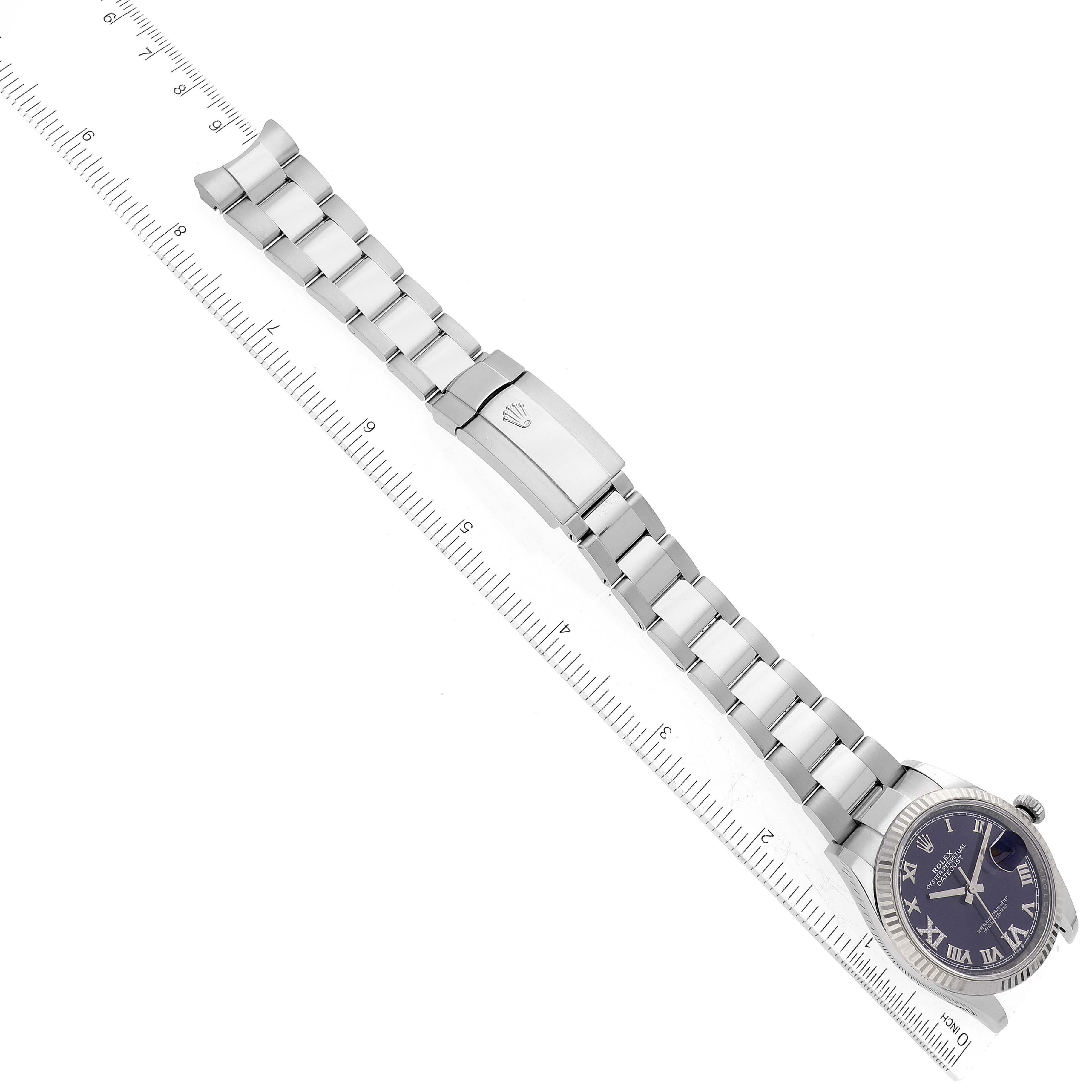 The image shows a top-down view of a Rolex Datejust 126234 Men's Stainless Steel Purple Dial 126234 Men's Stainless Steel Purple Dial watch with a silver bracelet and a clasp, accompanied by a measuring ruler.