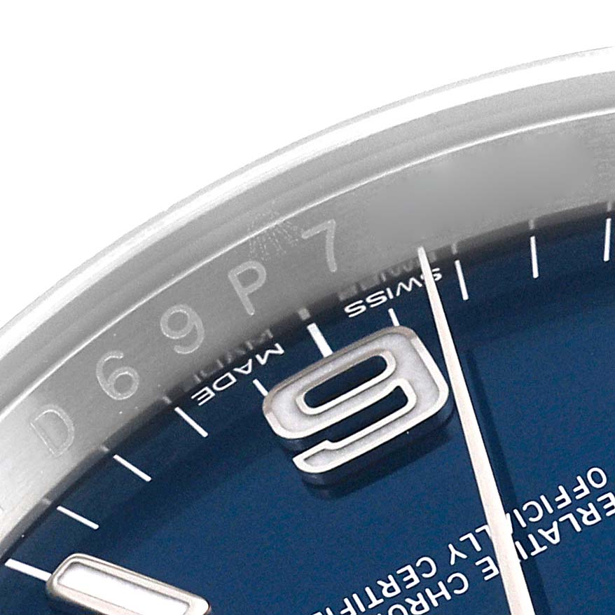 The image shows a close-up of the dial and bezel of a Rolex Oyster Perpetual 116000 Men
s Stainless Steel Blue Dial 116000 Men
s Stainless Steel Blue Dial watch, highlighting the number 9.