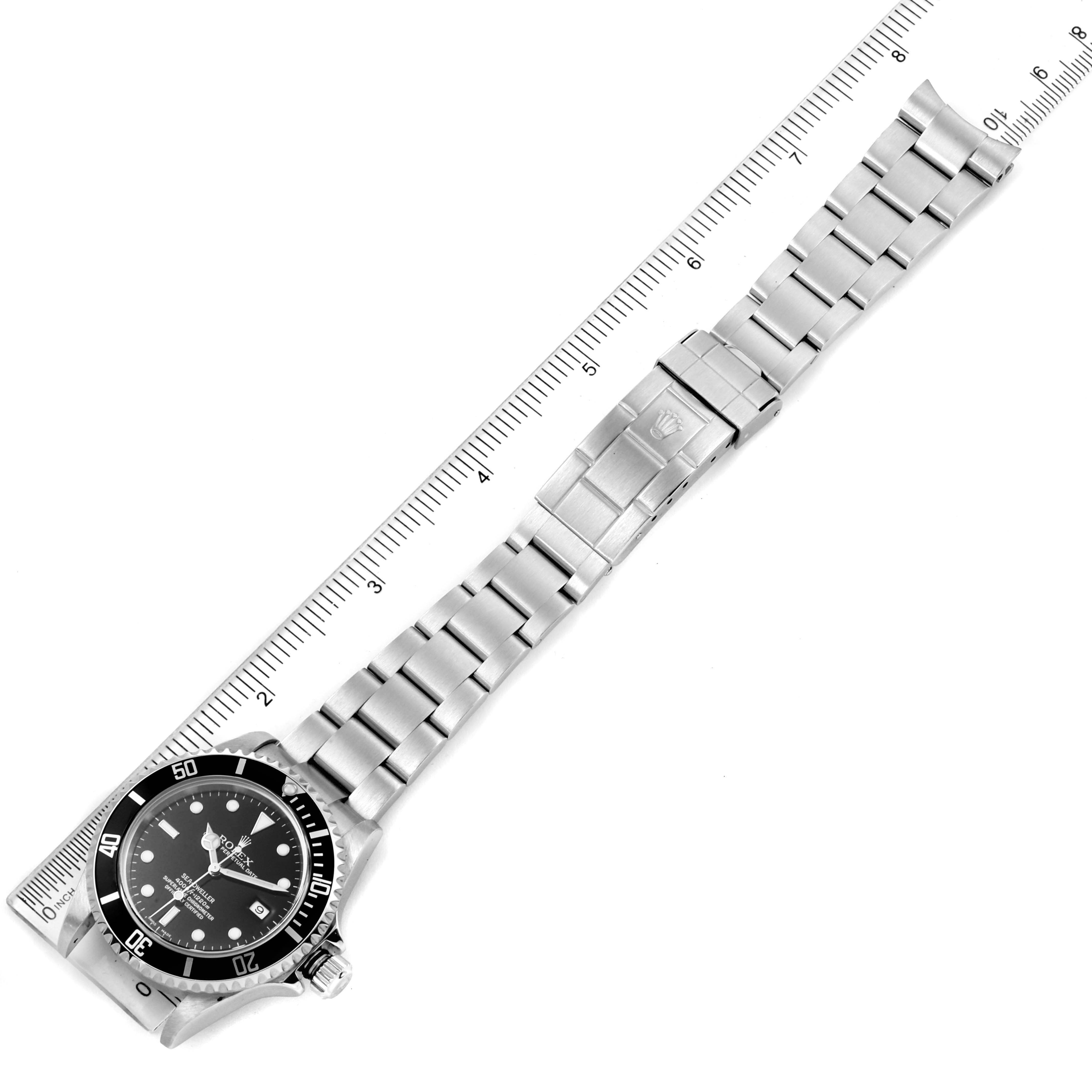 The image shows a top-down view of the Rolex Sea-Dweller 16600 Men
s Stainless Steel Black Dial 16600 Men
s Stainless Steel Black Dial watch with its stainless steel bracelet and clasp, positioned next to a ruler.