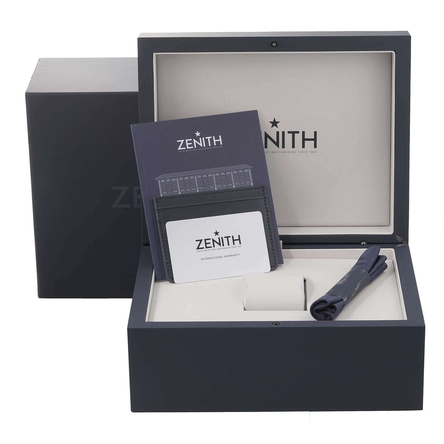 The image shows the Zenith El Primero watch box, warranty card, manual, and cleaning cloth from a top-front angle.