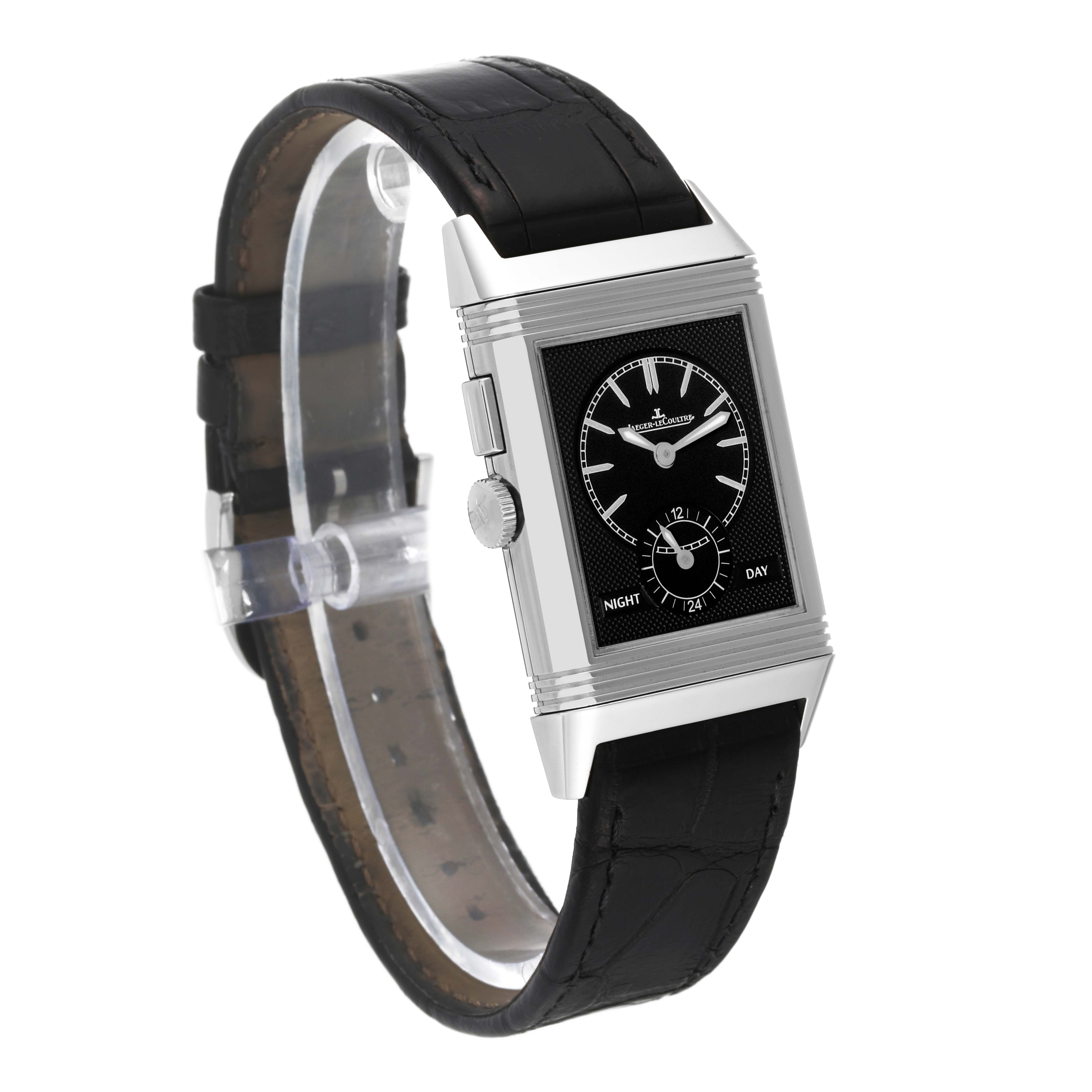 The image shows a Jaeger-LeCoultre Reverso watch at an oblique angle, highlighting its rectangular case, black dial, and black leather strap.