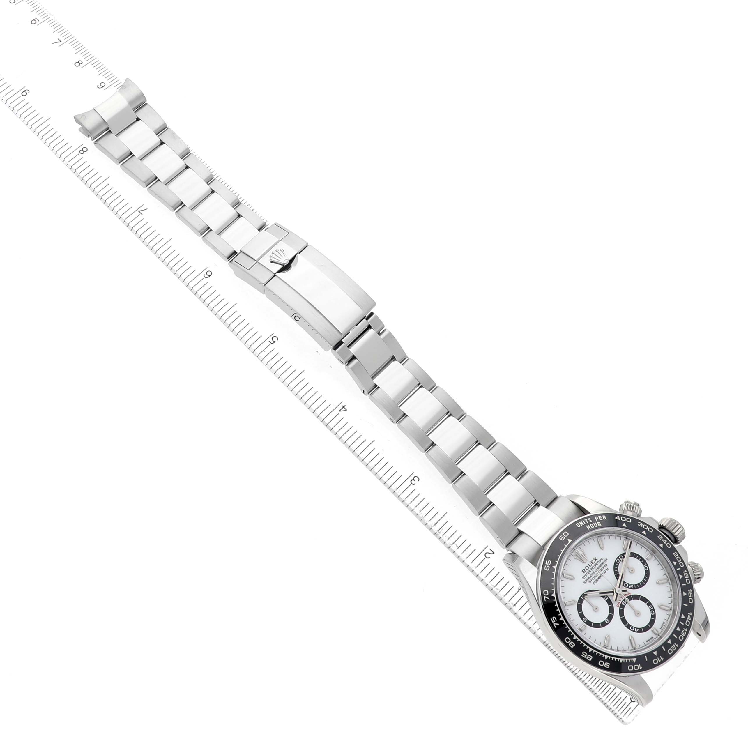 The image shows a Rolex Daytona 126500 Men's Stainless Steel White Dial watch laid flat with its bracelet open, captured from a top-down angle alongside a ruler for scale.