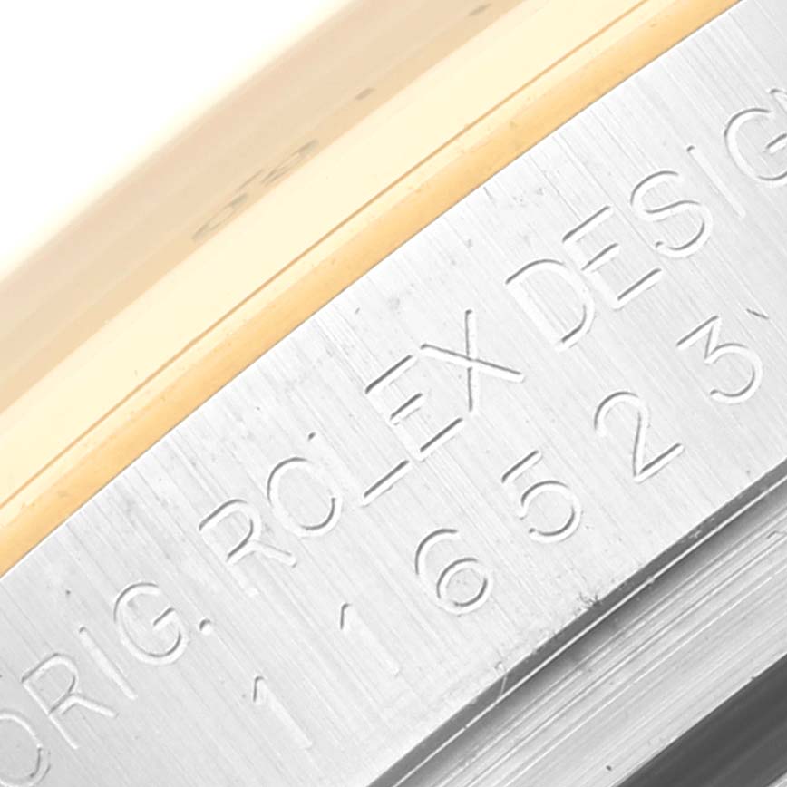 The image shows a close-up of the engraved side of a Rolex Daytona 116523 Men's Steel and Gold (two tone) Mother of Pearl Dial 116523 Men's Steel and Gold (two tone) Mother of Pearl Dial watch case.